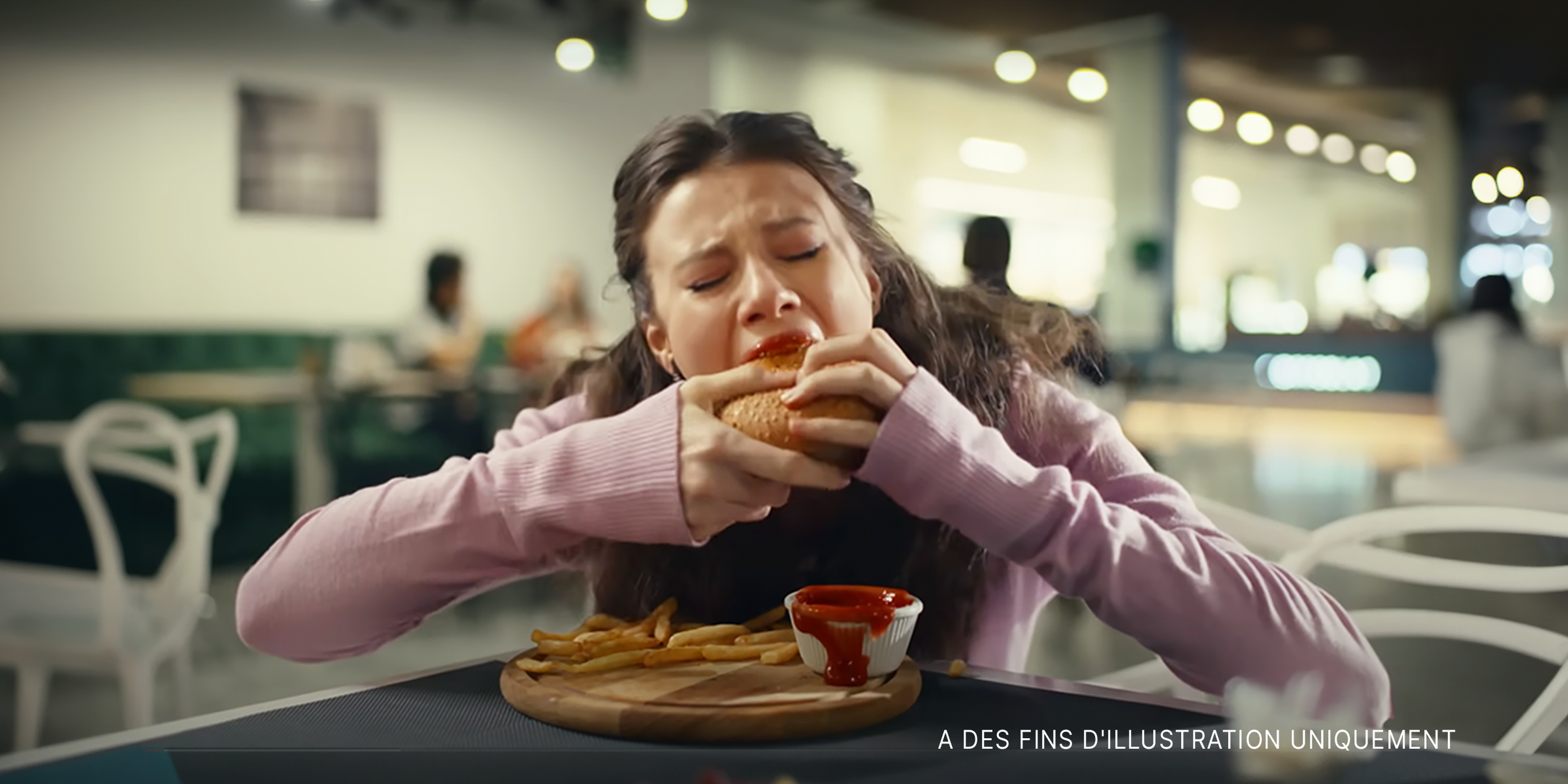 Une fille mange frénétiquement un hamburger | Source : YouTube/LoveBuster
