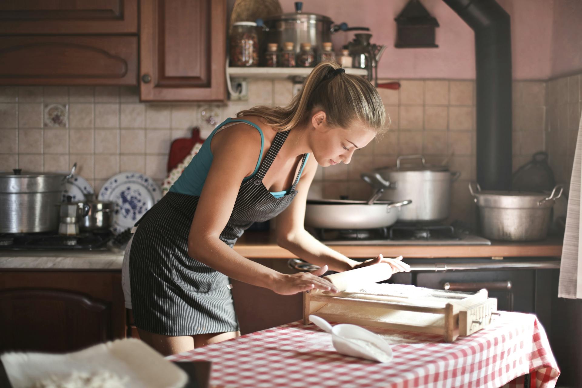 Une jeune femme roule de la pâte pour la cuisson dans une cuisine | Source : Pexels