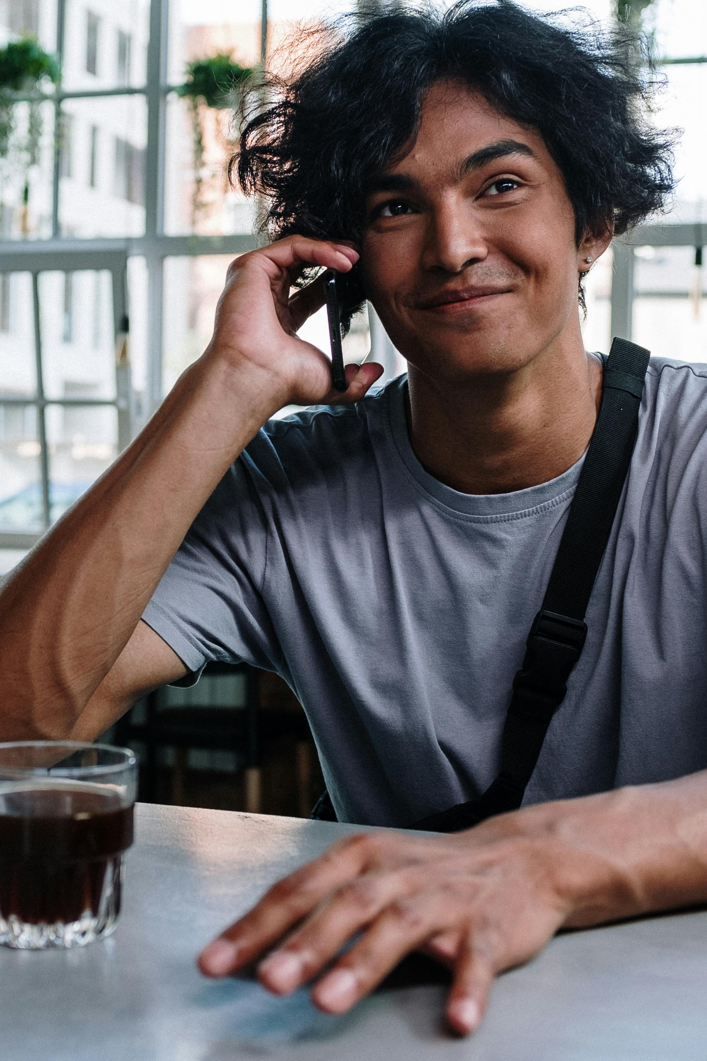 Un homme heureux qui parle au téléphone tout en prenant un verre | Source : Pexels