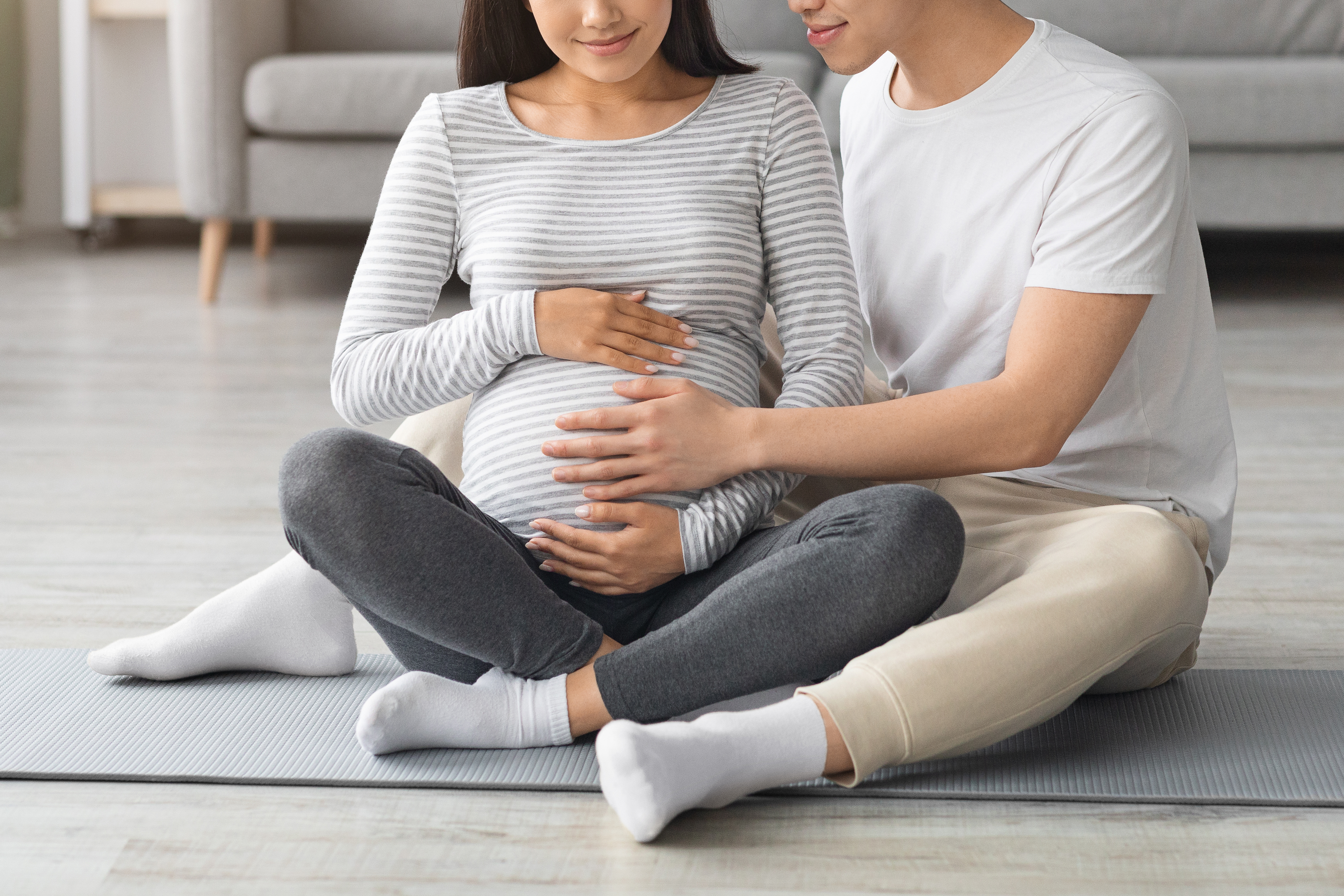 Homme assis avec sa femme enceinte sur un tapis de yoga | Source : Shutterstock