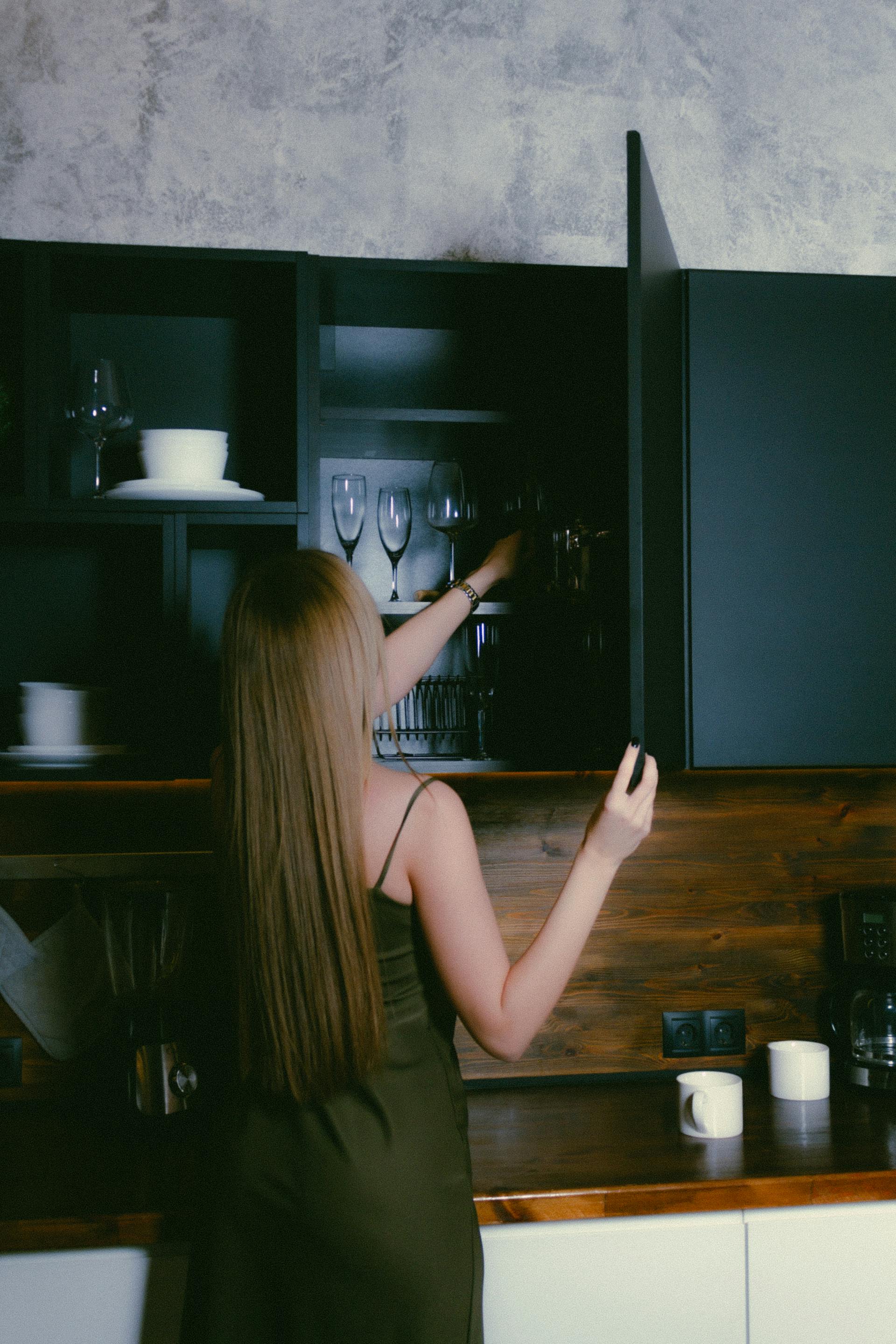 Une femme range des objets dans les placards de la cuisine | Source : Pexels