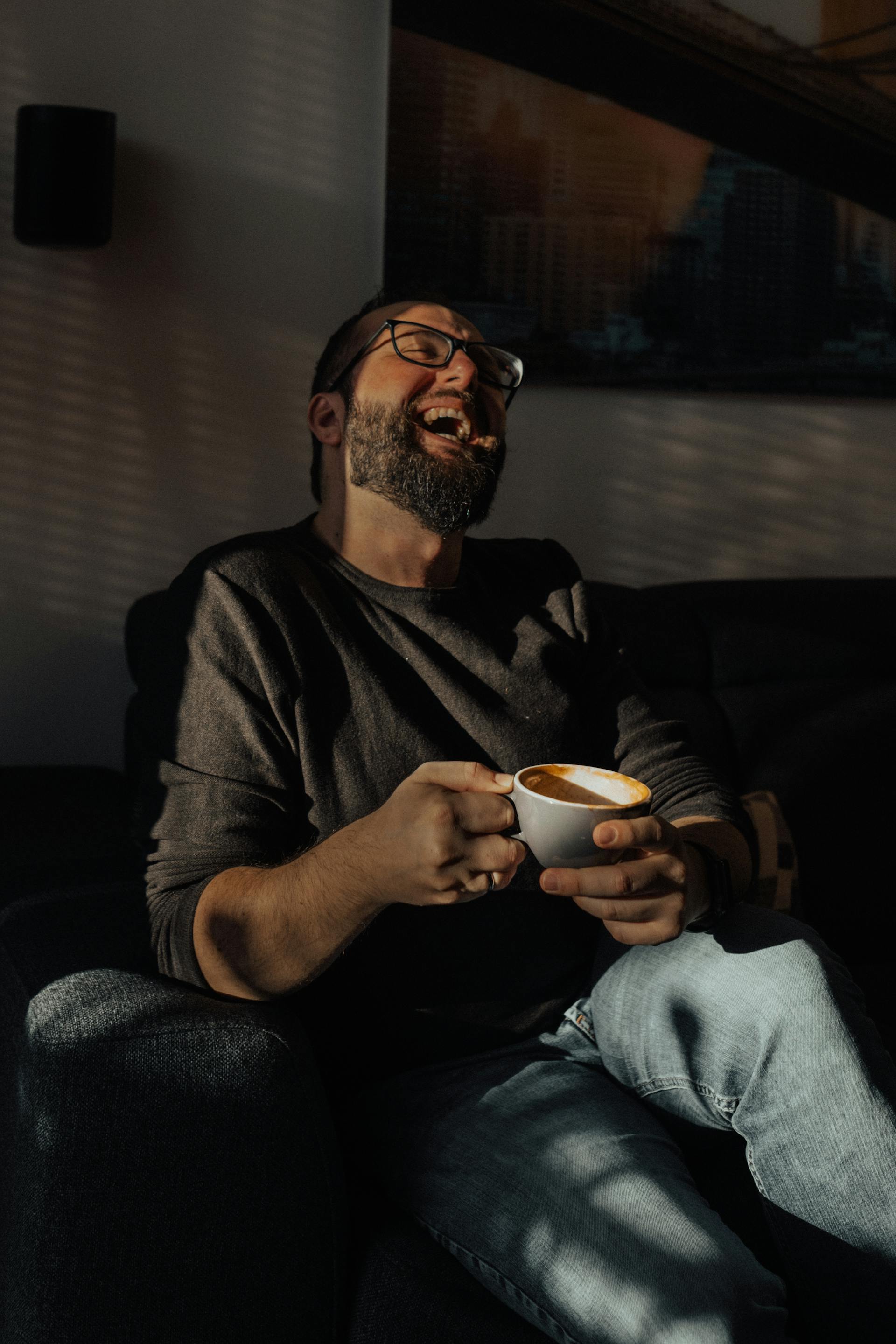 Un homme qui rit en tenant une tasse de café | Source : Pexels
