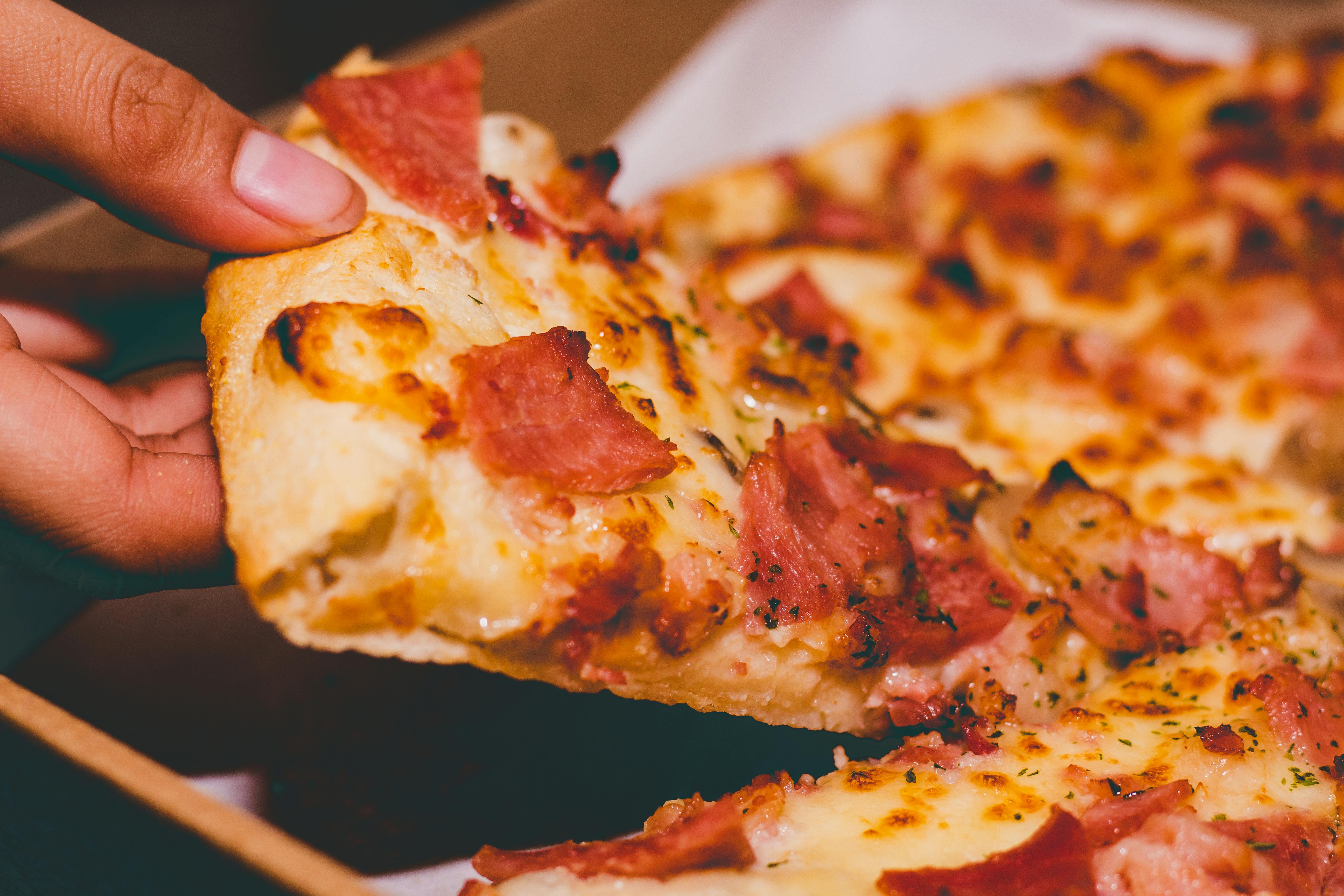 Une personne tenant une part de pizza | Source : Pexels