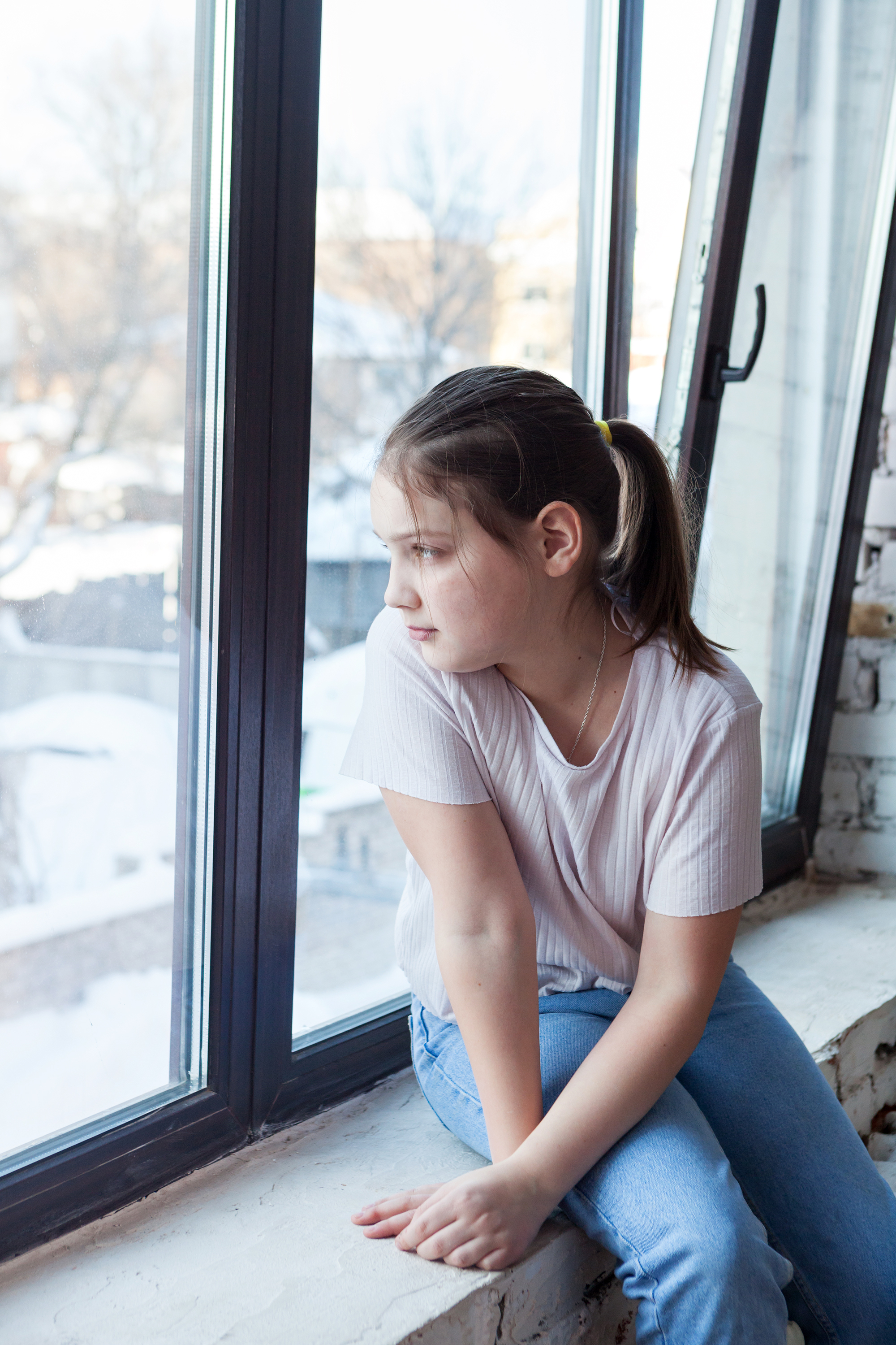 Jeune fille regardant par la fenêtre | Source : Shutterstock