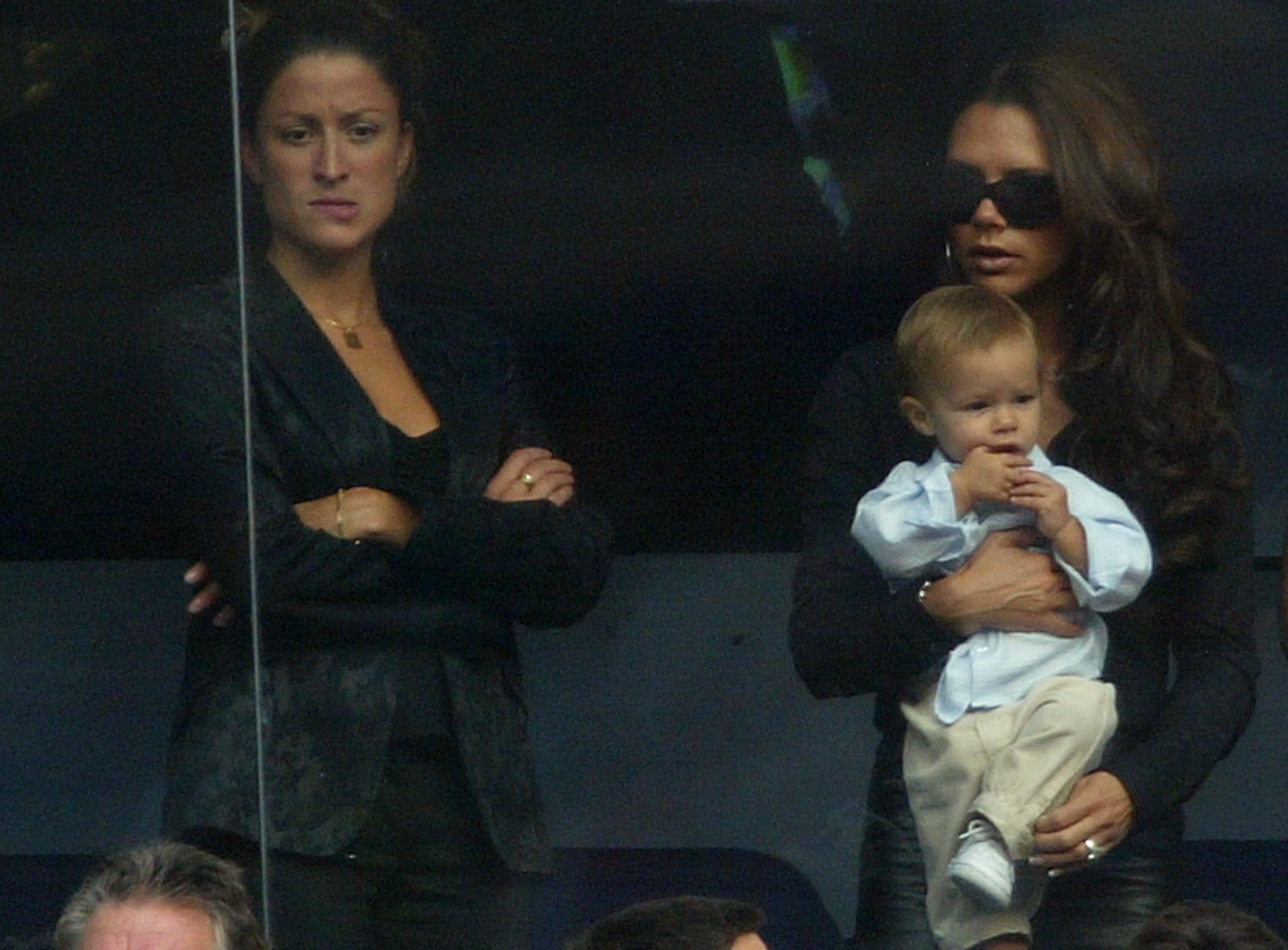 Victoria Beckham tient son fils Romeo à côté de Rebecca Loos, l'assistante personnelle de David Beckham, pendant le match de la Primera Liga espagnole entre le Real Madrid et Valladolid au stade Santiago Bernabeu, le 13 septembre 2003, à Madrid, en Espagne. | Source : Getty Images