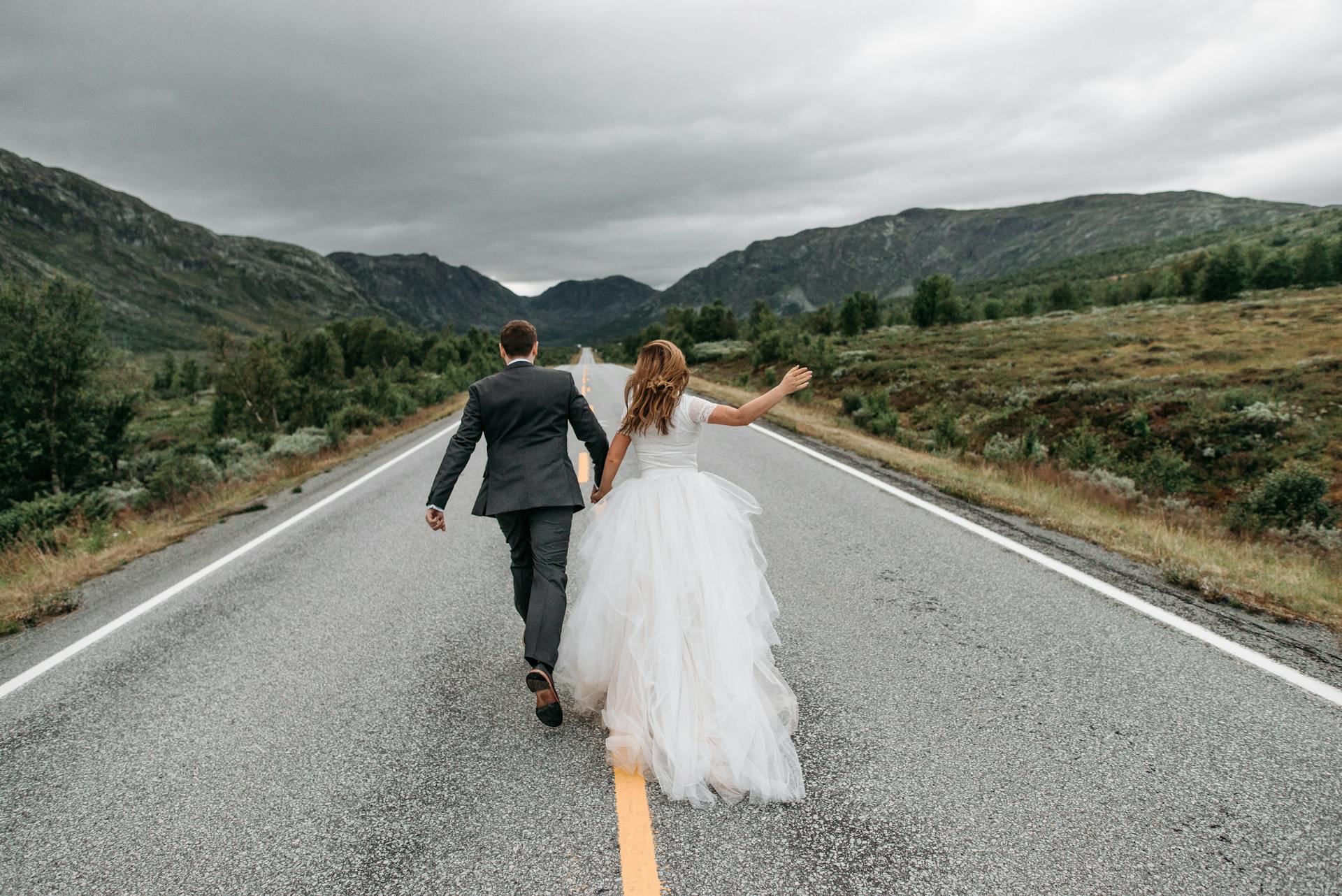 Une mariée et un marié qui courent sur une route | Source : Pexels