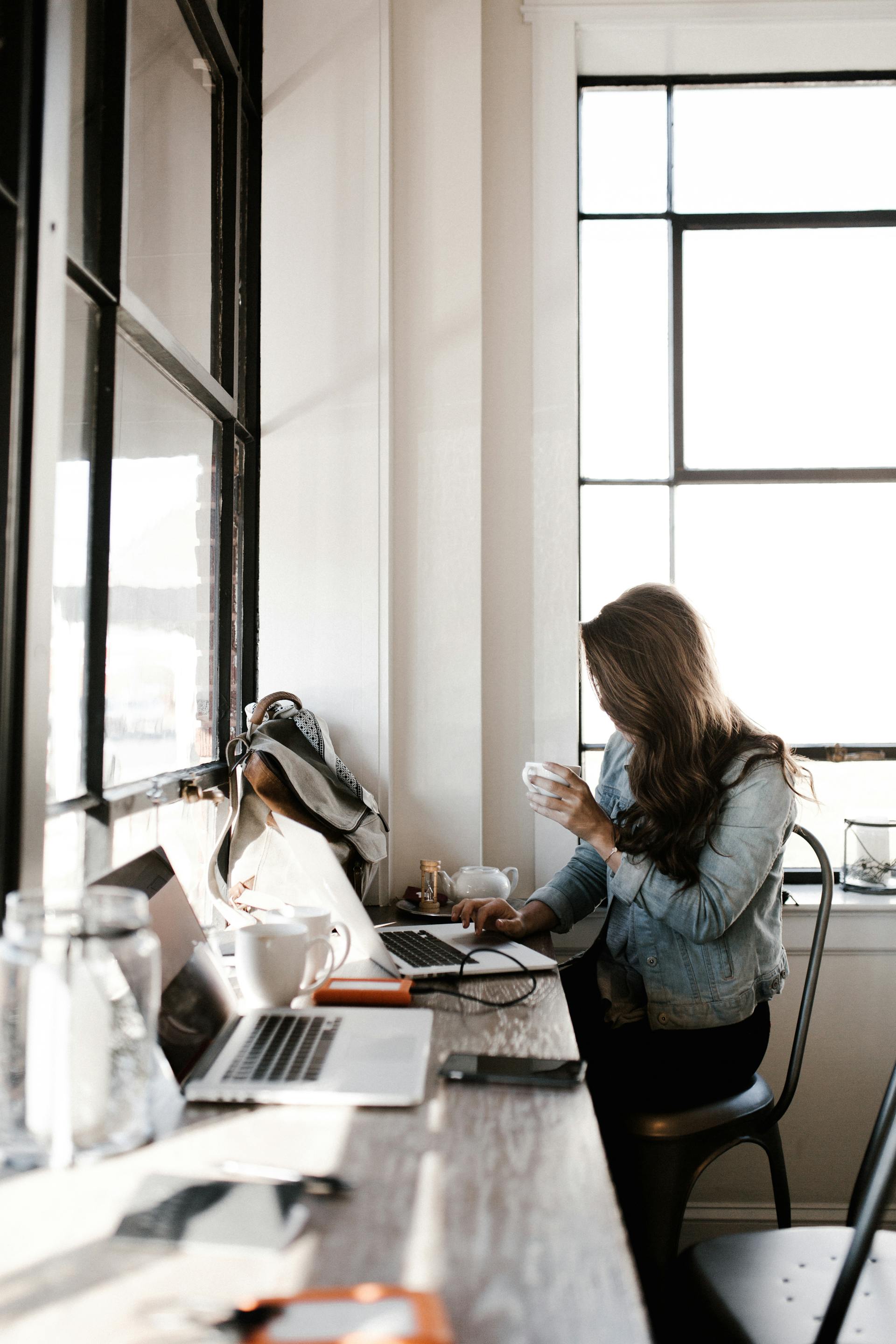 Une jeune femme travaillant sur son ordinateur portable, assise à côté d'un bureau | Source : Pexels