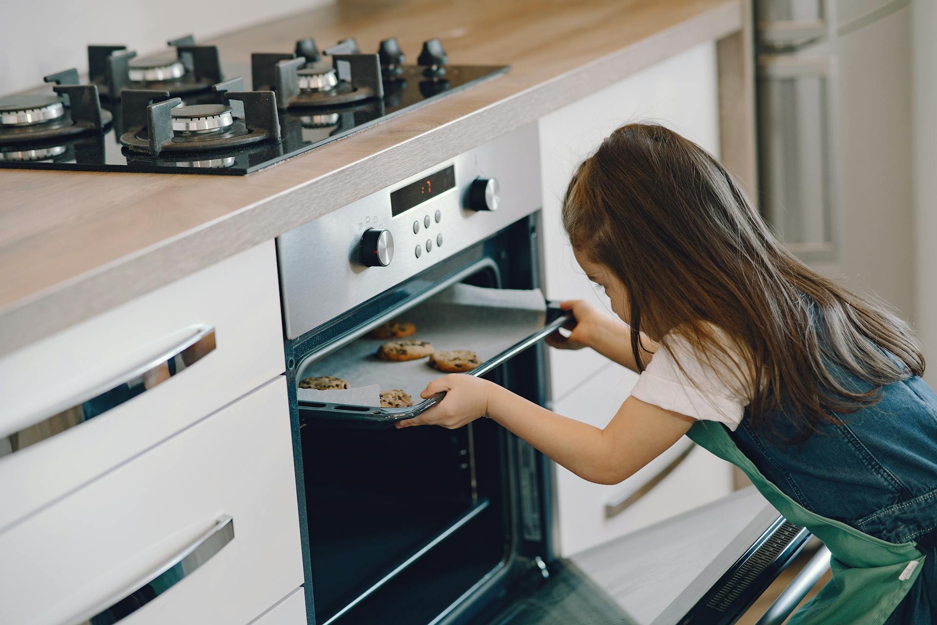 Une fille qui met un plateau de biscuits dans le four | Source : Pexels