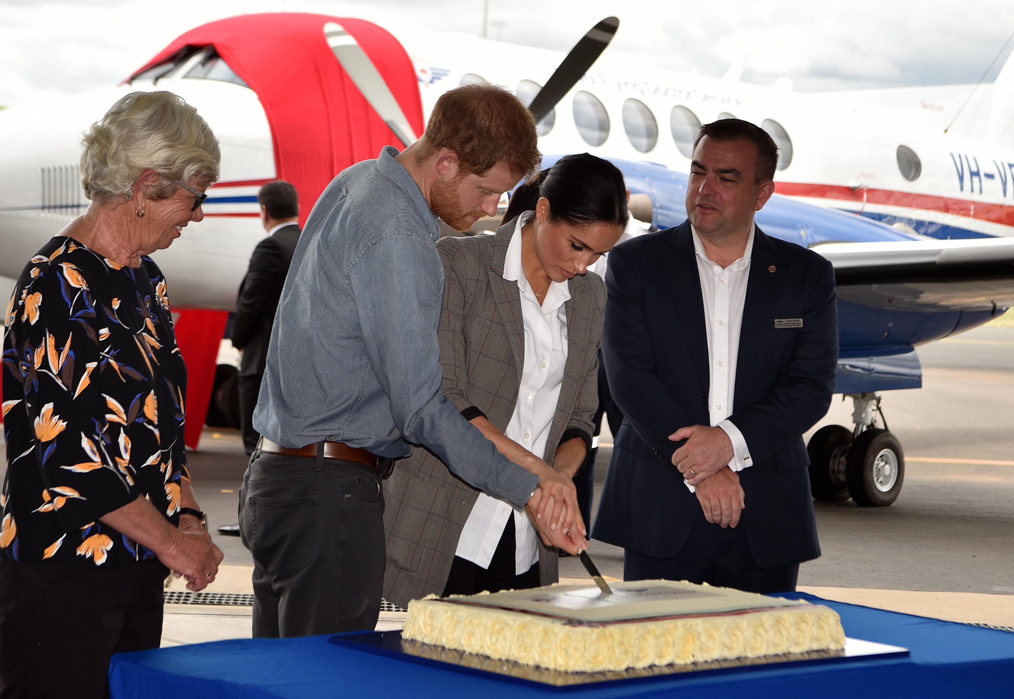 Le prince Harry et Meghan Markle coupent un gâteau d'anniversaire commémorant les 90 ans du Royal Flying Doctor Service australien à l'aéroport régional de Dubbo, en Australie, le 17 octobre 2018 | Source : Getty Images