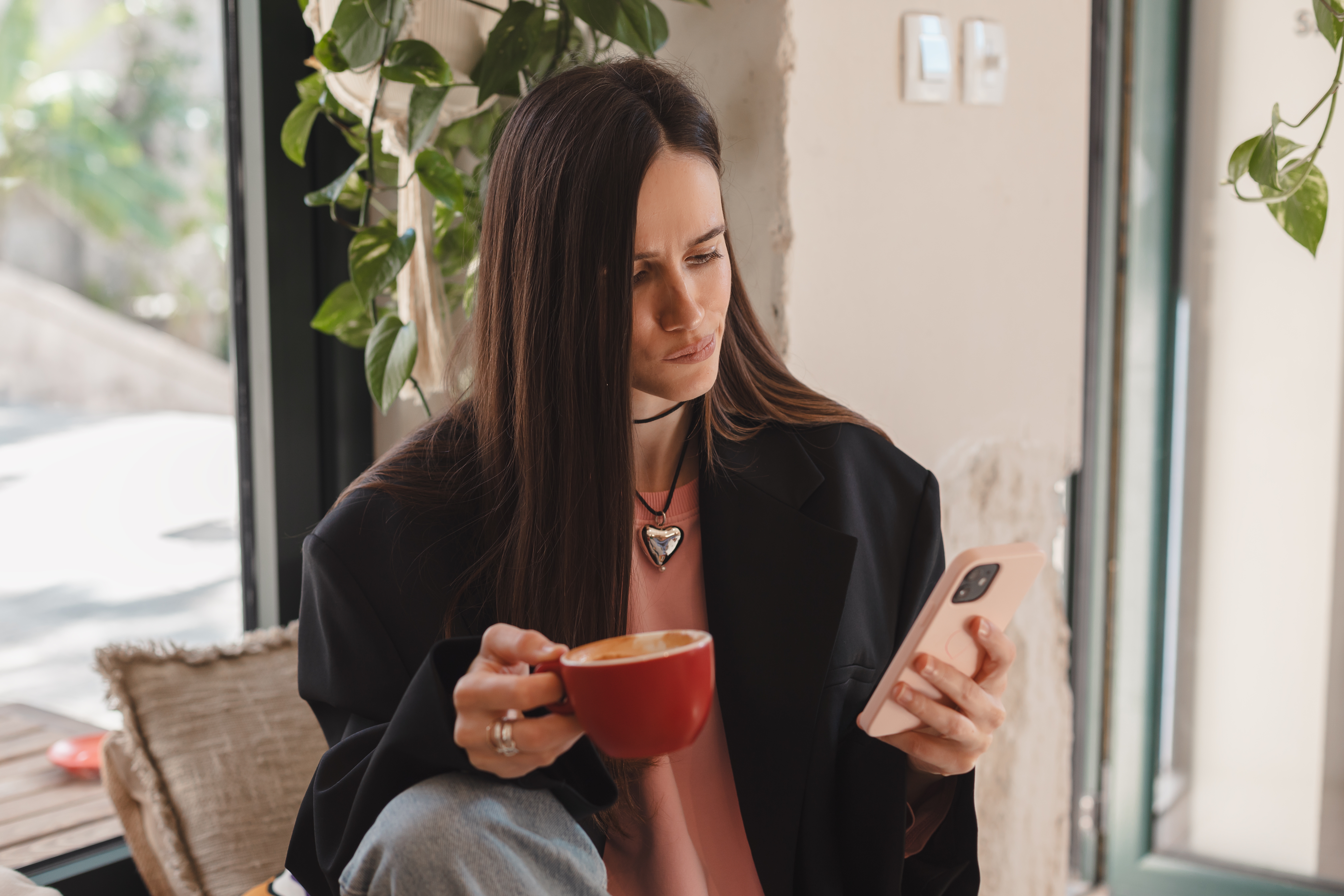Une femme utilisant son téléphone tout en tenant une tasse de café | Source : Shutterstock