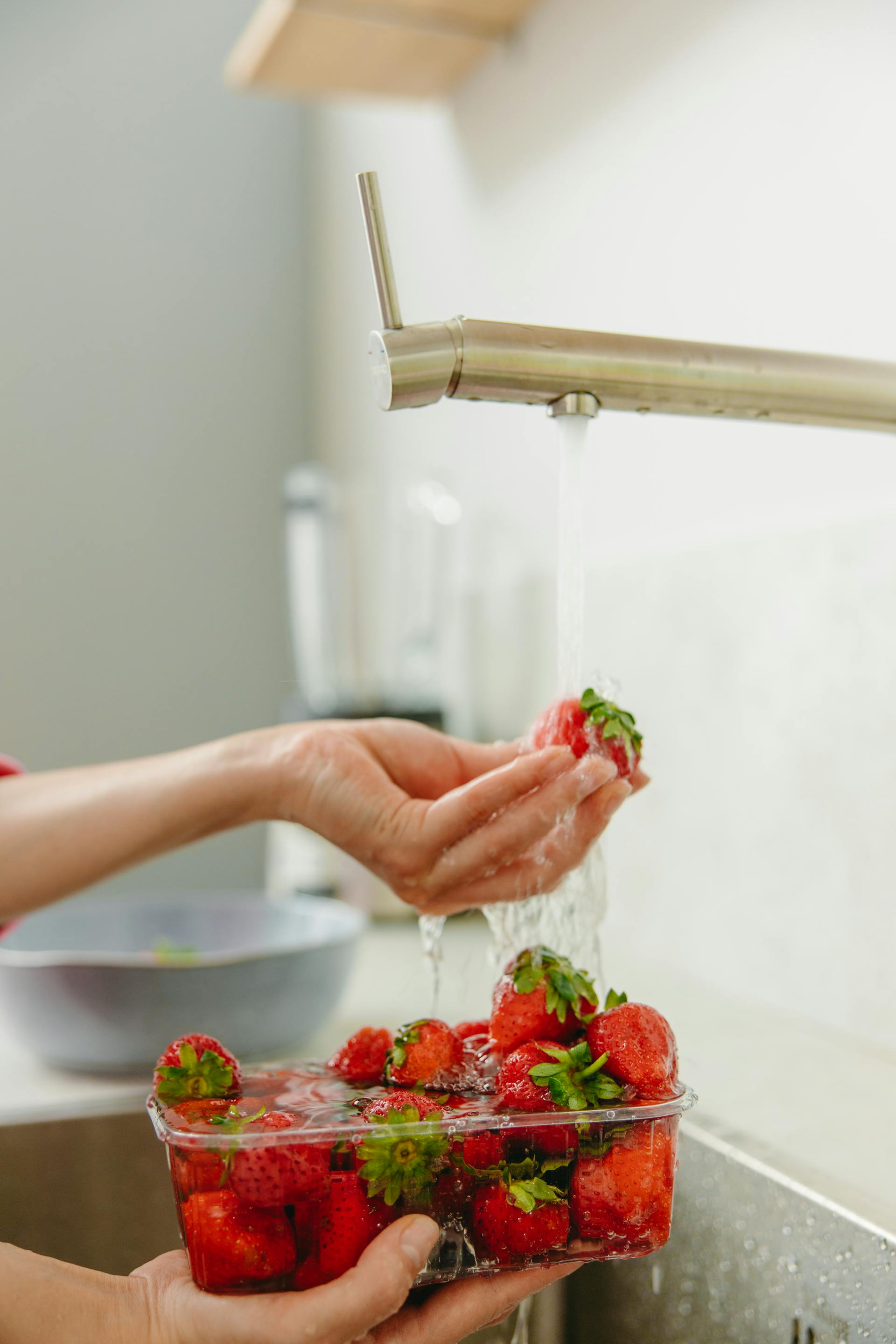 Gros plan sur une femme qui lave des fraises à l'eau courante dans la cuisine | Source : Pexels