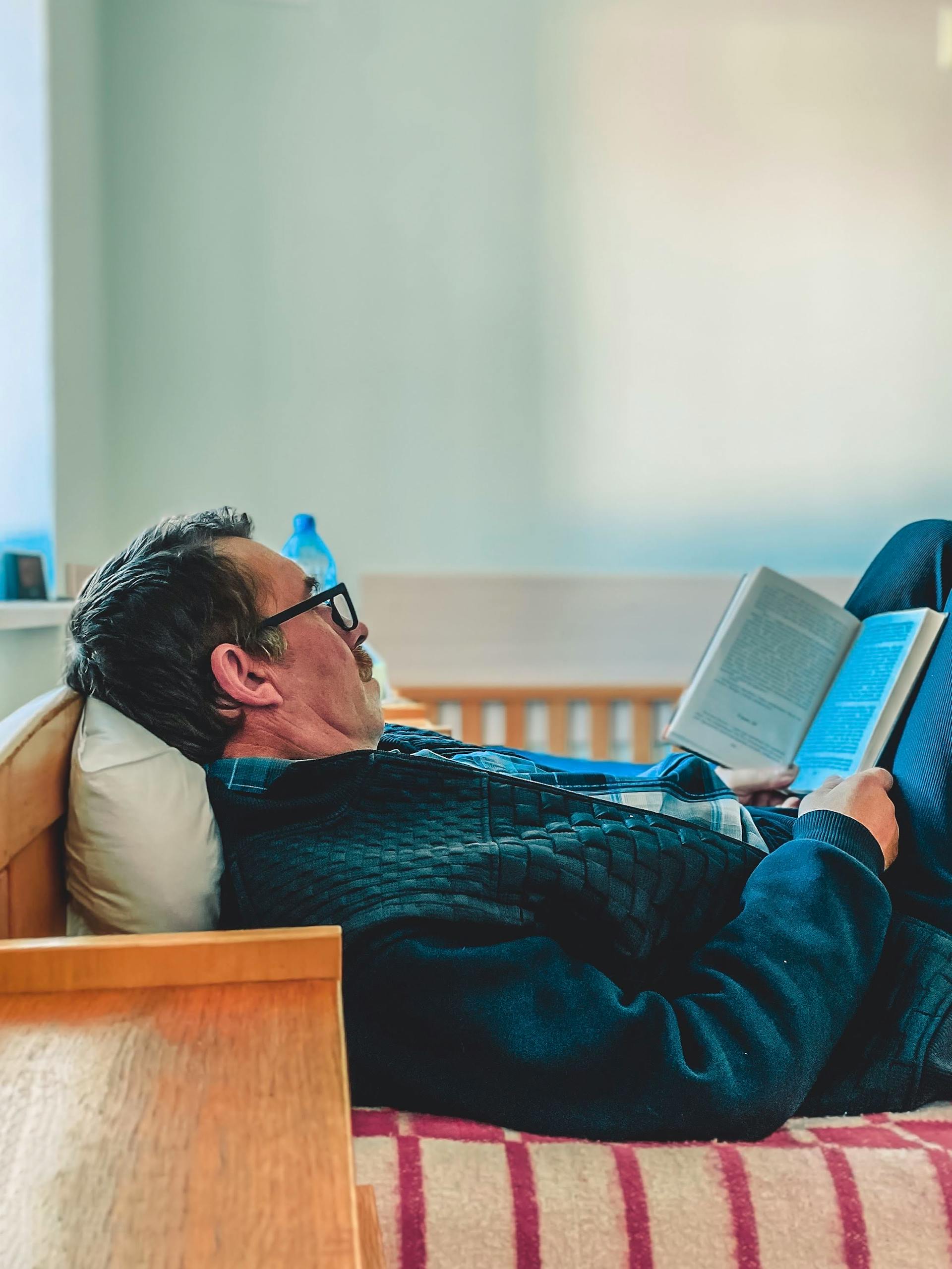 Un homme allongé dans son lit en train de lire | Source : Pexels