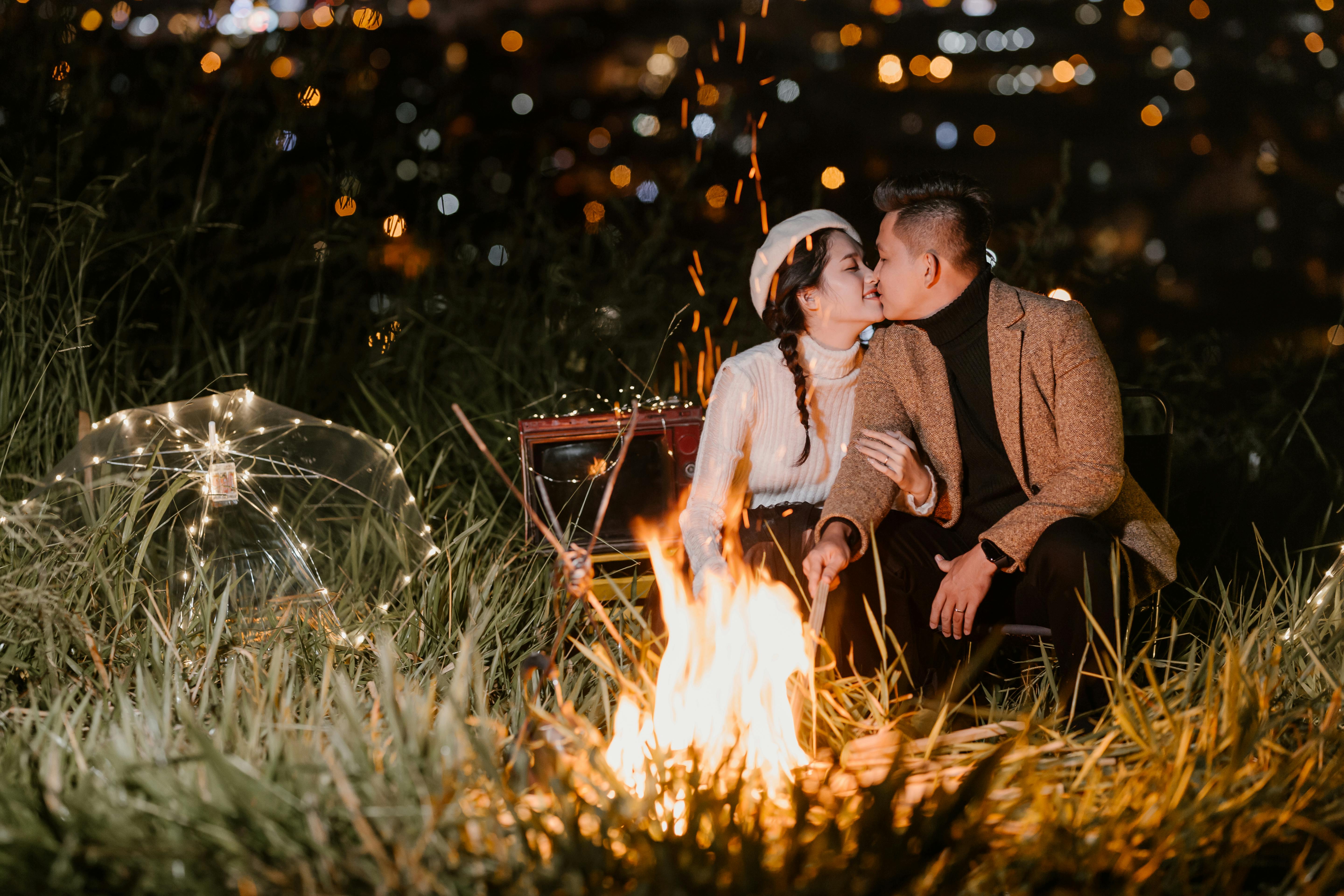 Un couple s'embrasse au clair de lune avec un feu qui brûle | Source : Pexels