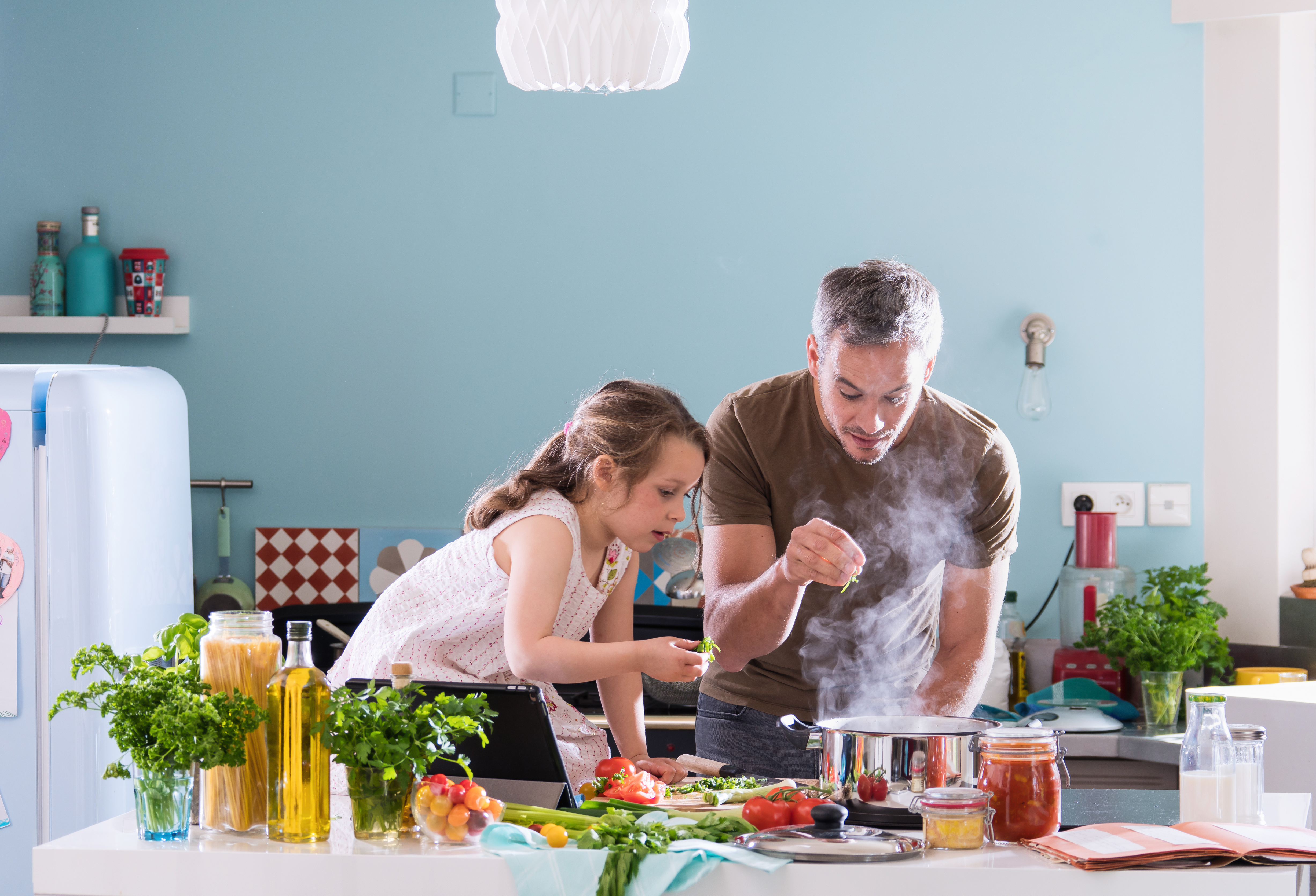 Un père en train de cuisiner avec sa petite fille dans la cuisine | Source : Shutterstock