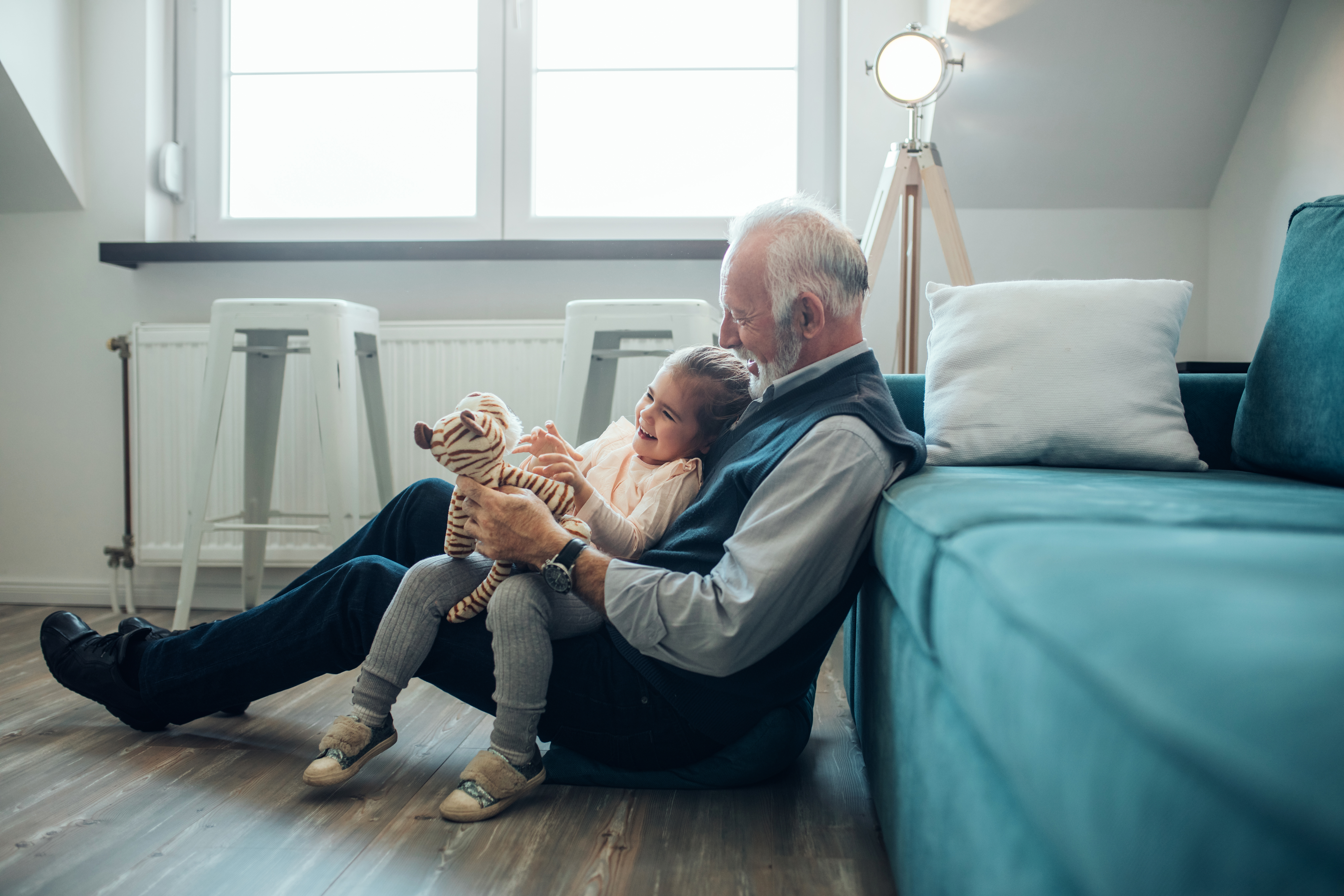 Un grand-père assis par terre avec sa petite-fille sur ses genoux | Source : Shutterstock