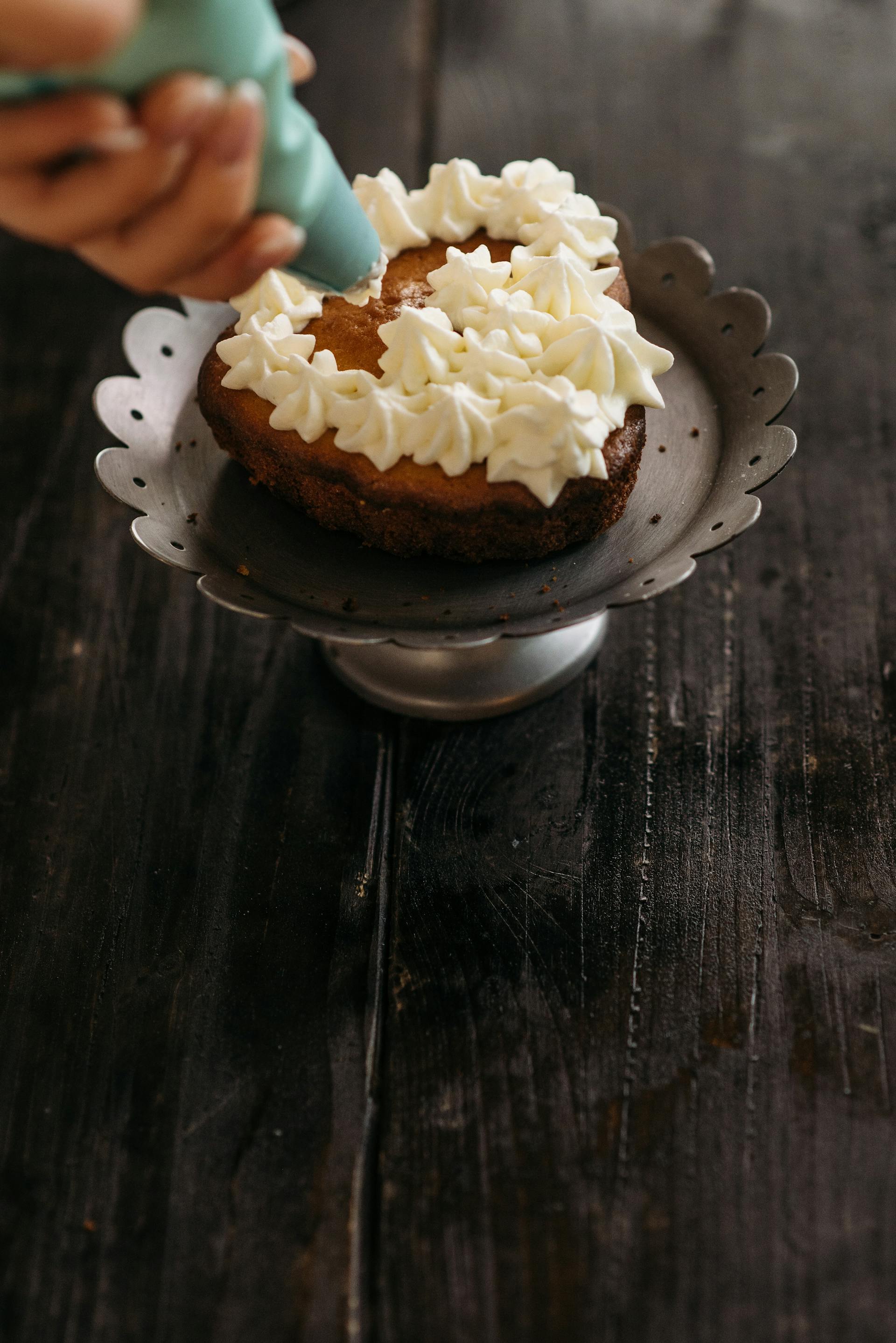 Une personne en train d'appliquer du glaçage sur un gâteau | Source : Pexels