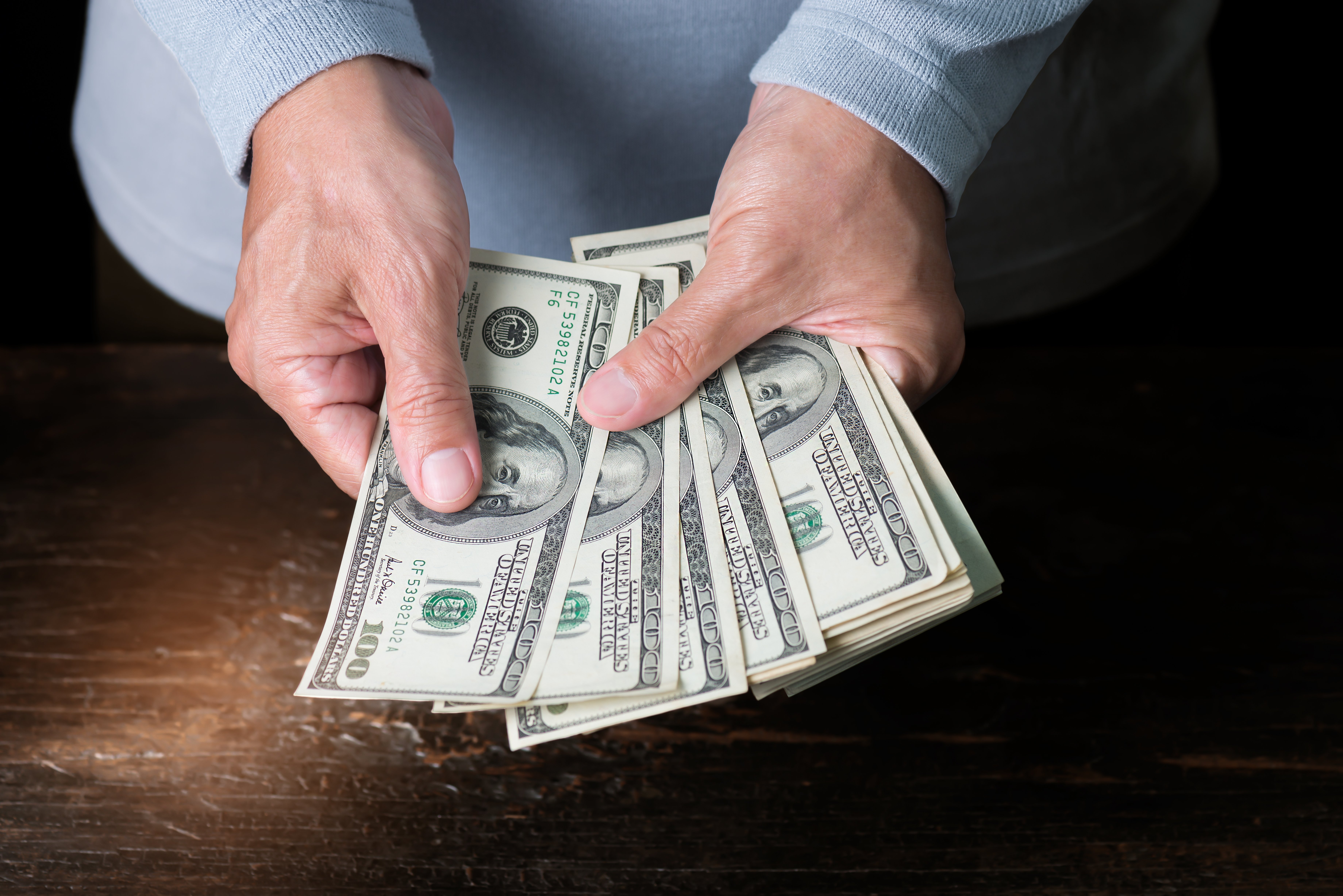 Un homme qui tient plusieurs billets d'argent | Photo : Shutterstock