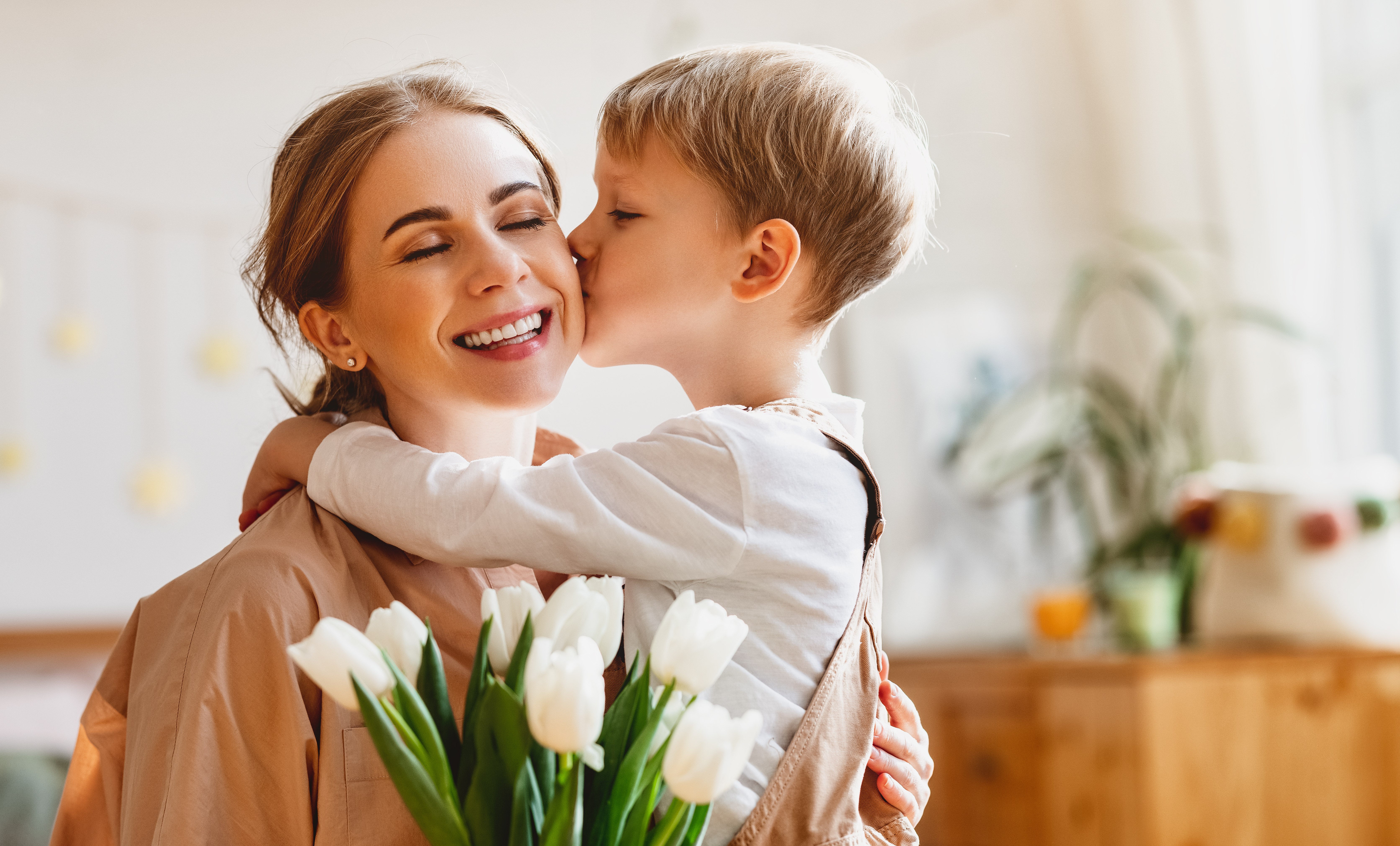 Une mère qui ferme les yeux et tient un bouquet de tulipes pendant que son fils l'embrasse sur la joue | Source : Shutterstock