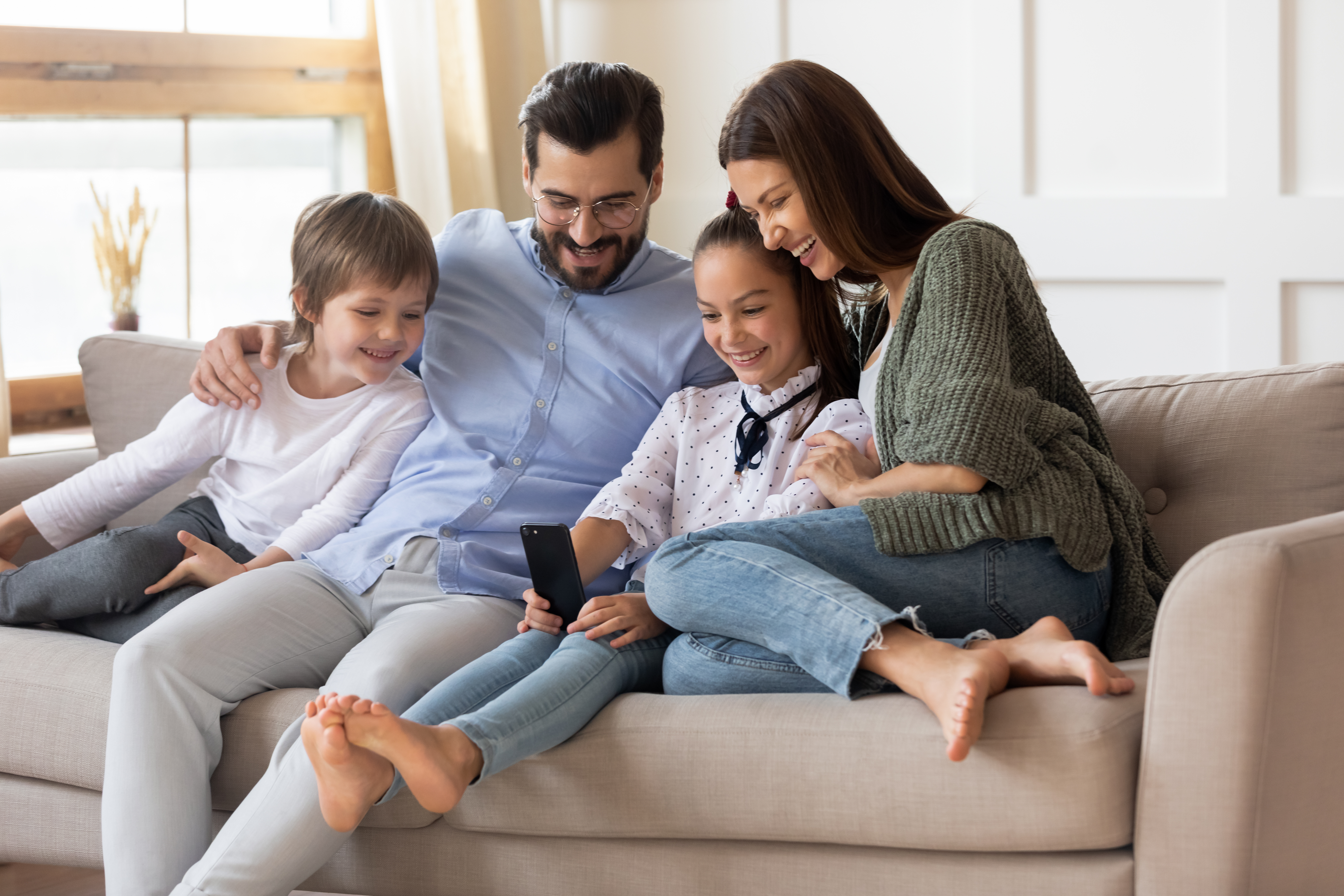 Des parents heureux se détendent à la maison avec leurs jeunes enfants | Source : Shutterstock