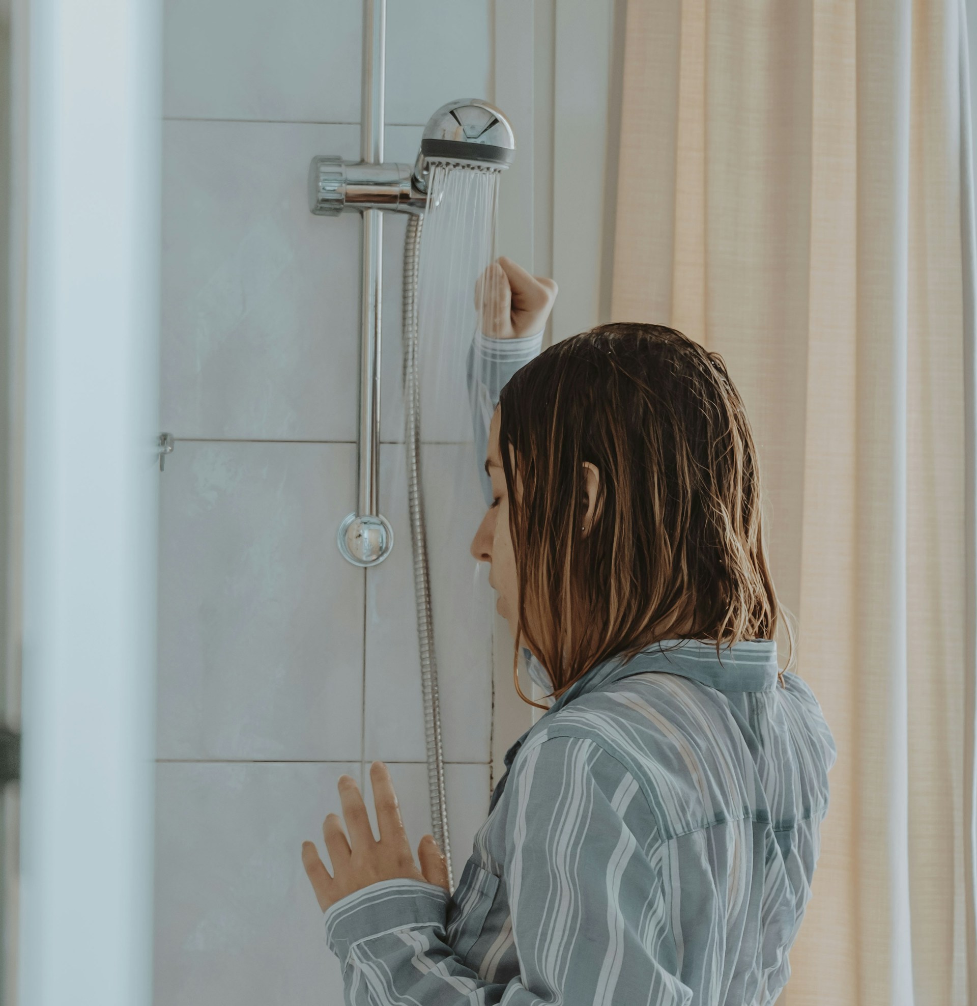 Une jeune femme déprimée et désespérée debout dans la douche | Source : Unsplash