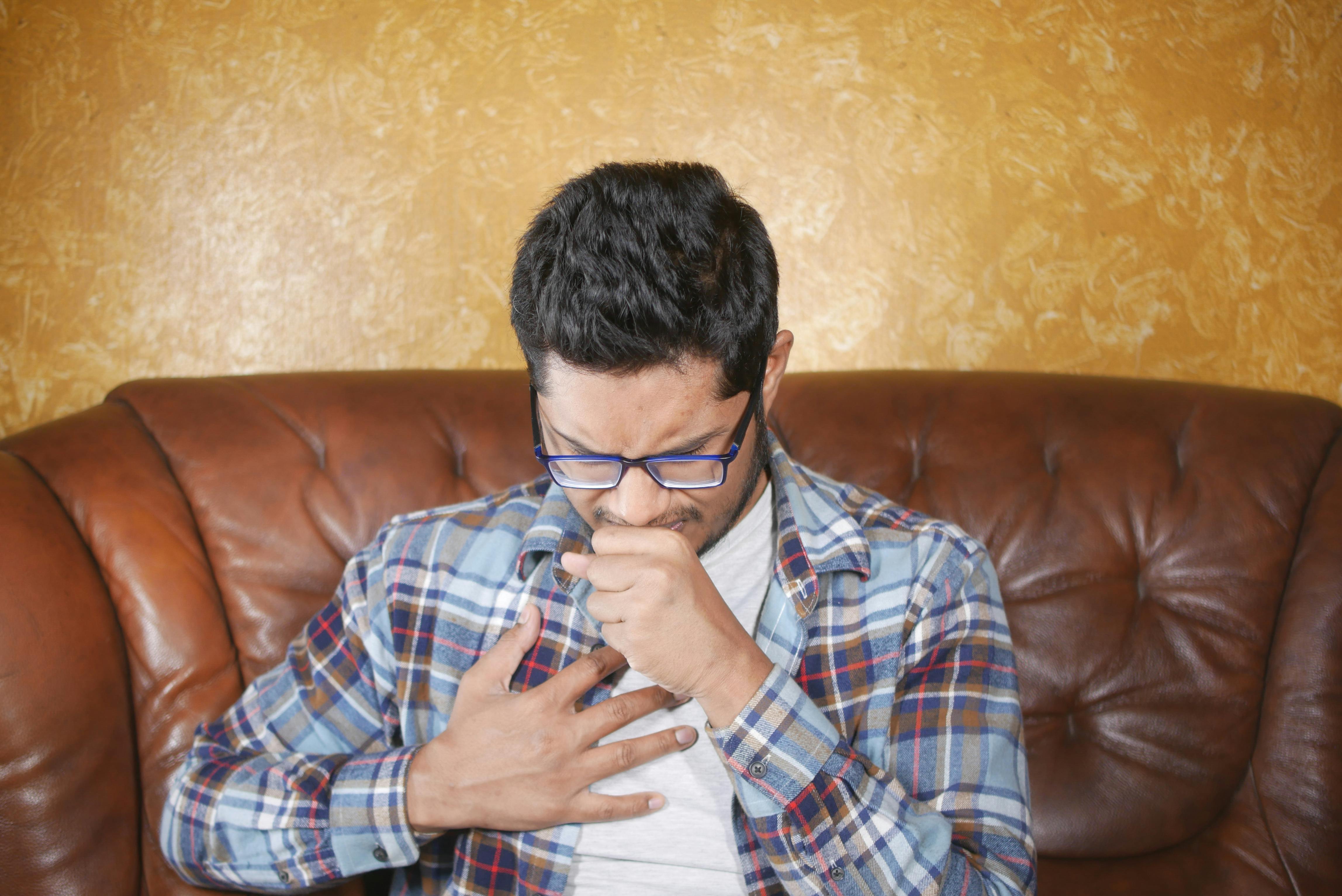 Un homme se tenant la poitrine alors qu'il tousse dans sa main | Source : Pexels