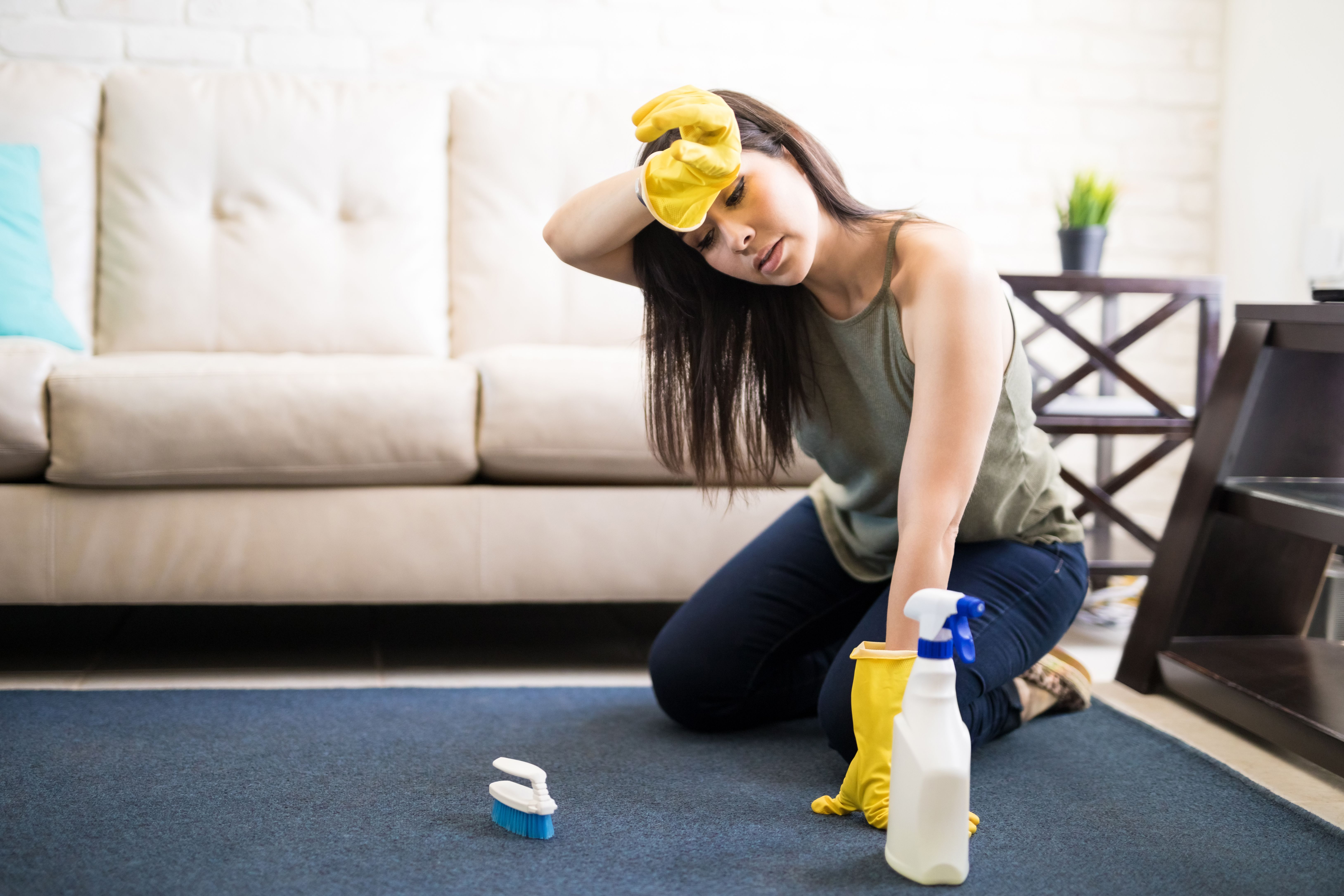 Une jeune femme en train de nettoyer le tapis. | Source : Getty Images