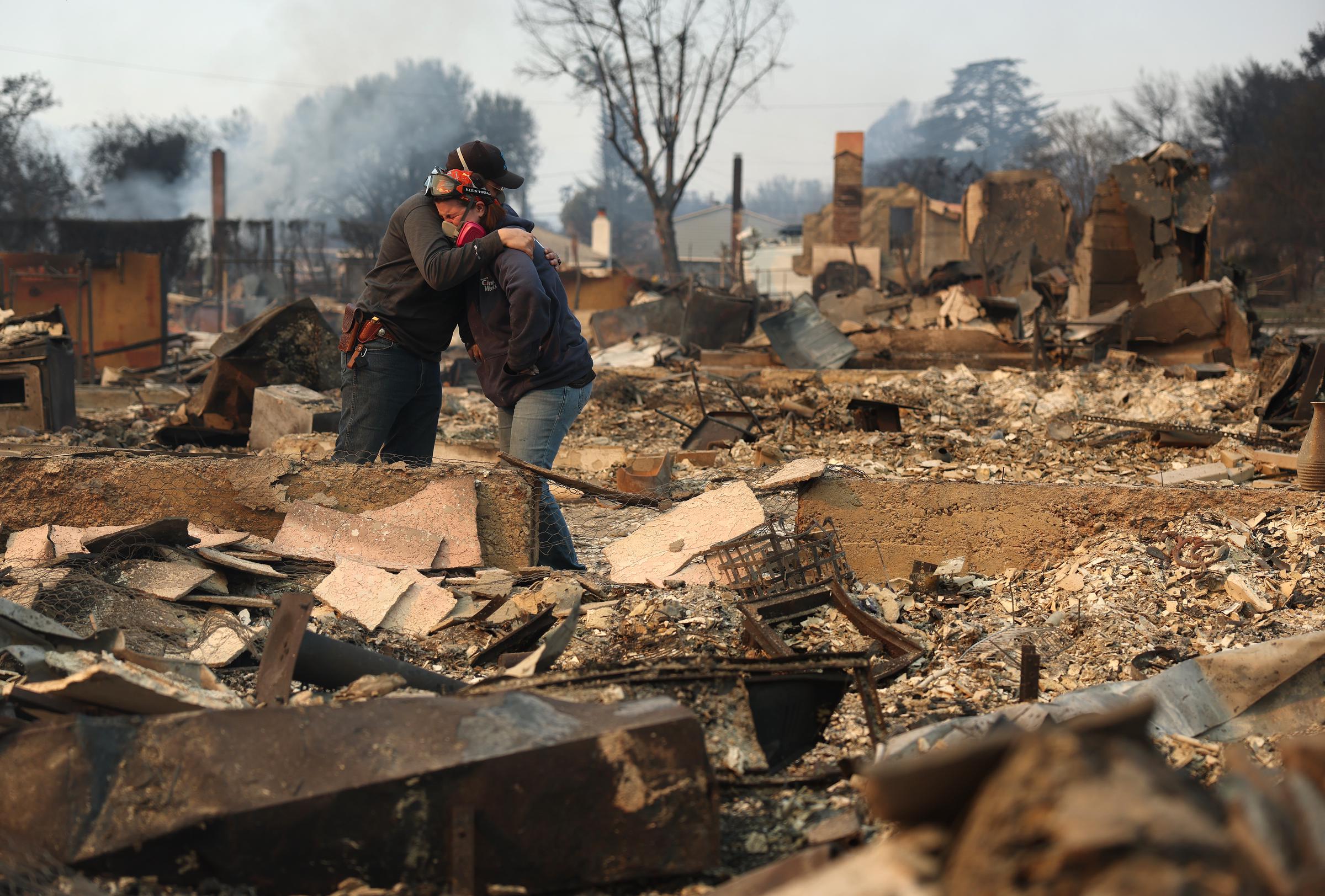 Khaled Fouad (à gauche) et Mimi Laine (à droite) s'embrassent alors qu'ils inspectent la propriété d'un membre de leur famille qui a été détruite par l'incendie Eaton, le 09 janvier 2025, à Altadena, en Californie | Source : Getty Images