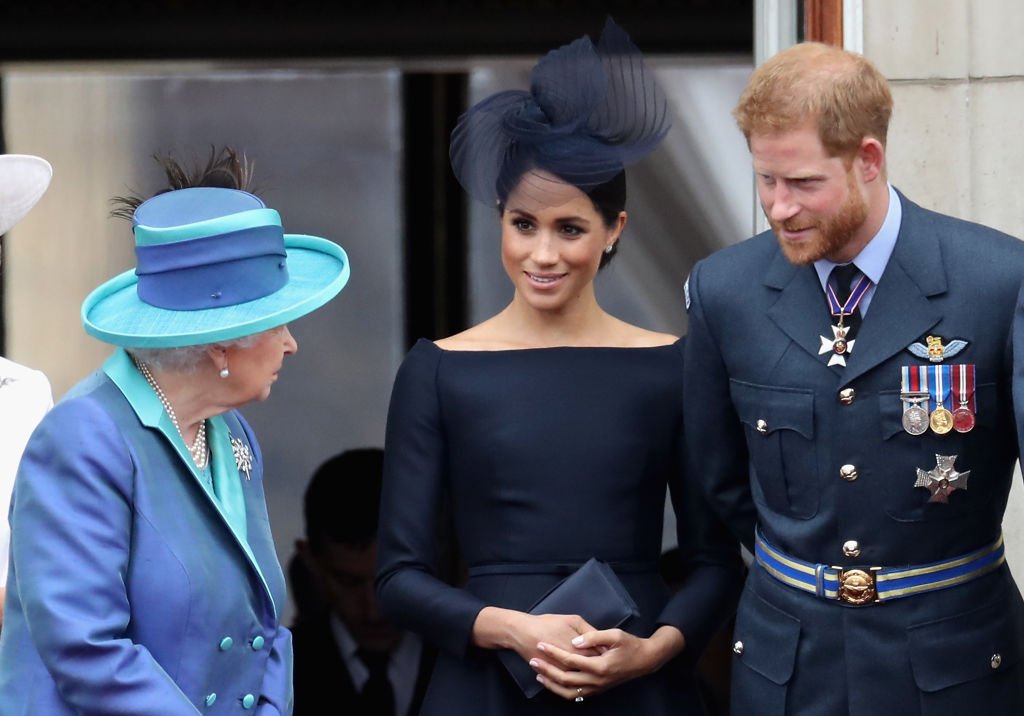 La reine Elizabeth II, Meghan, duchesse de Sussex, le prince Harry, duc de Sussex, regardent le défilé aérien de la RAF sur le balcon du palais de Buckingham, alors que les membres de la famille royale assistent aux événements marquant le centenaire de la RAF, le 10 juillet 2018 à Londres. | Photo : Getty Images