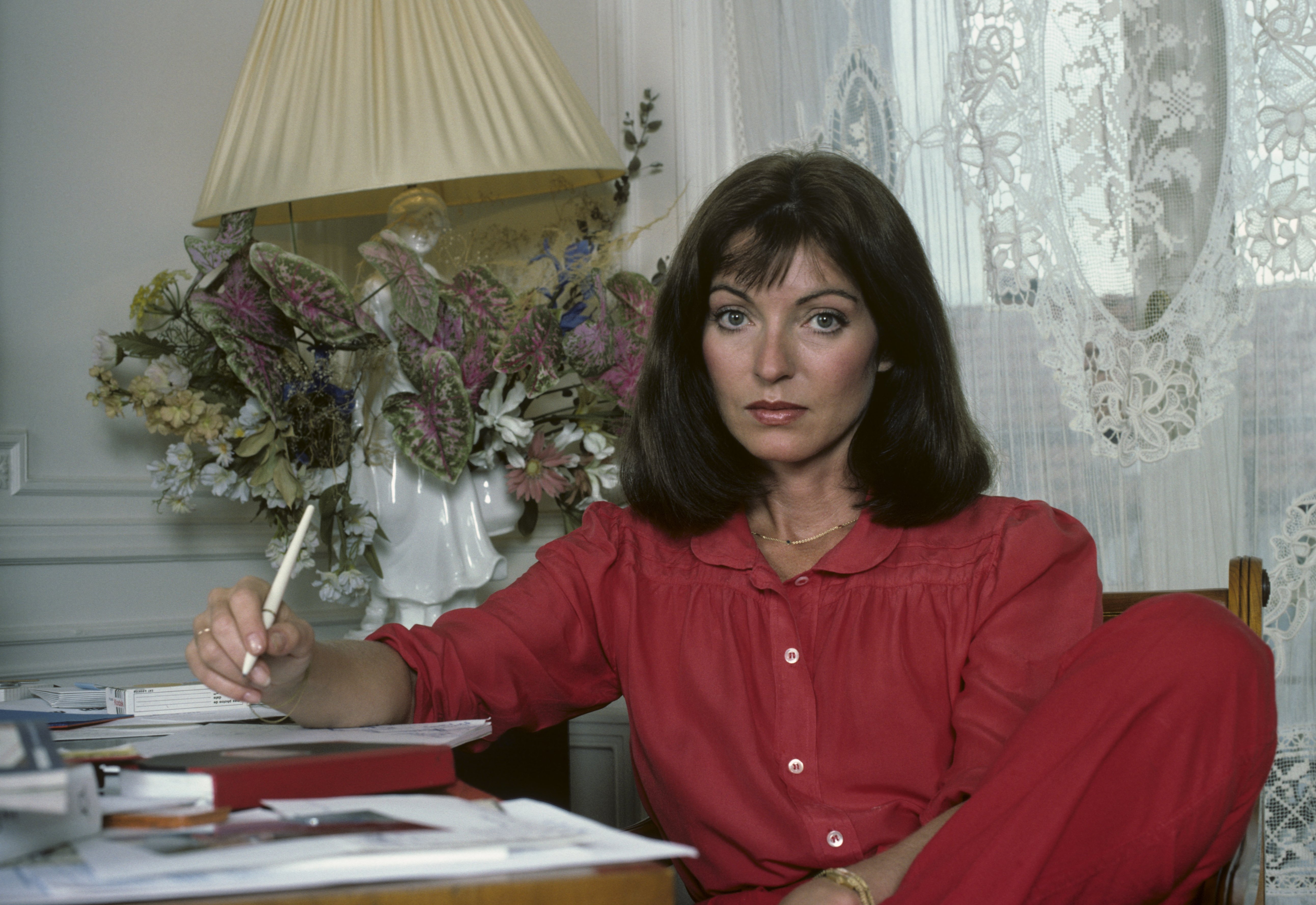 En France, à Paris, en septembre 1982, à l'occasion de la sortie du film 'L'As des As' de Gérard OURY, Marie-France PISIER, actrice, assise à son bureau, chez elle. | Photo : Getty Images