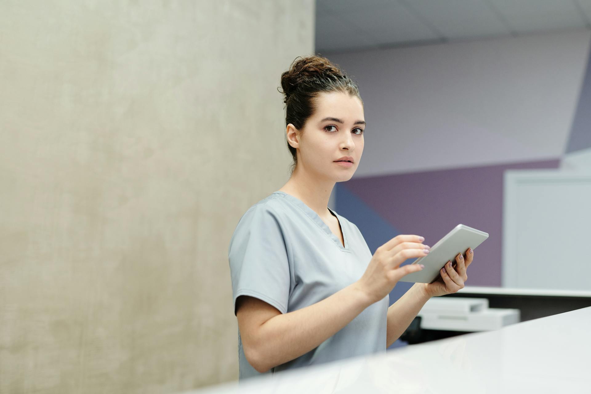 Une réceptionniste tenant une tablette informatique dans un hôpital | Source : Pexels