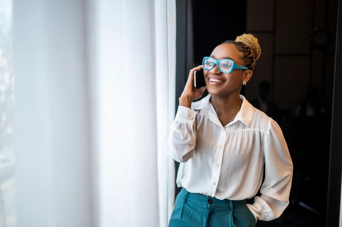 Une entrepreneuse noire souriante en train de parler au téléphone | Source : Getty Images