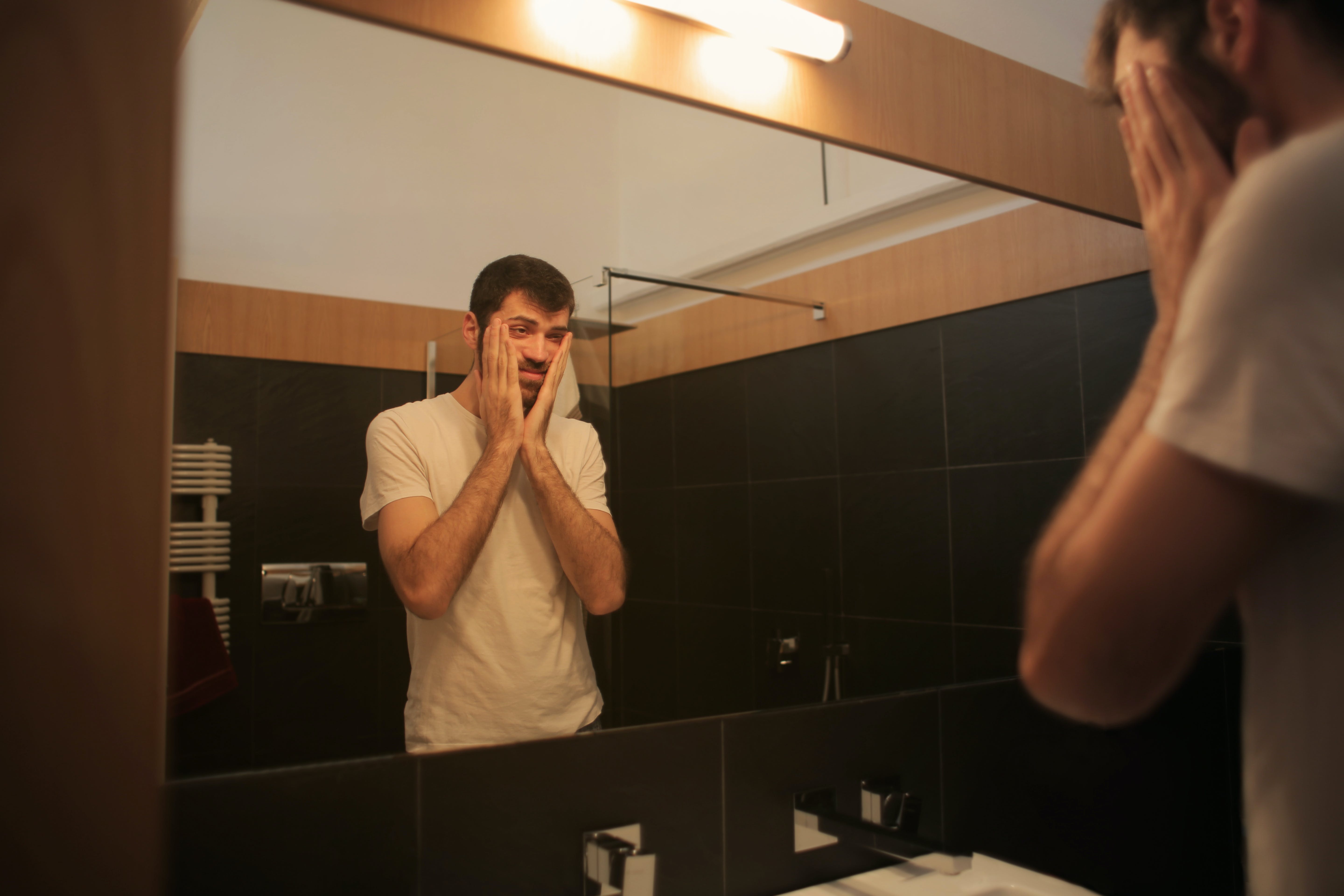 Un homme dans la salle de bain se regardant dans le miroir┃Source : Pexels