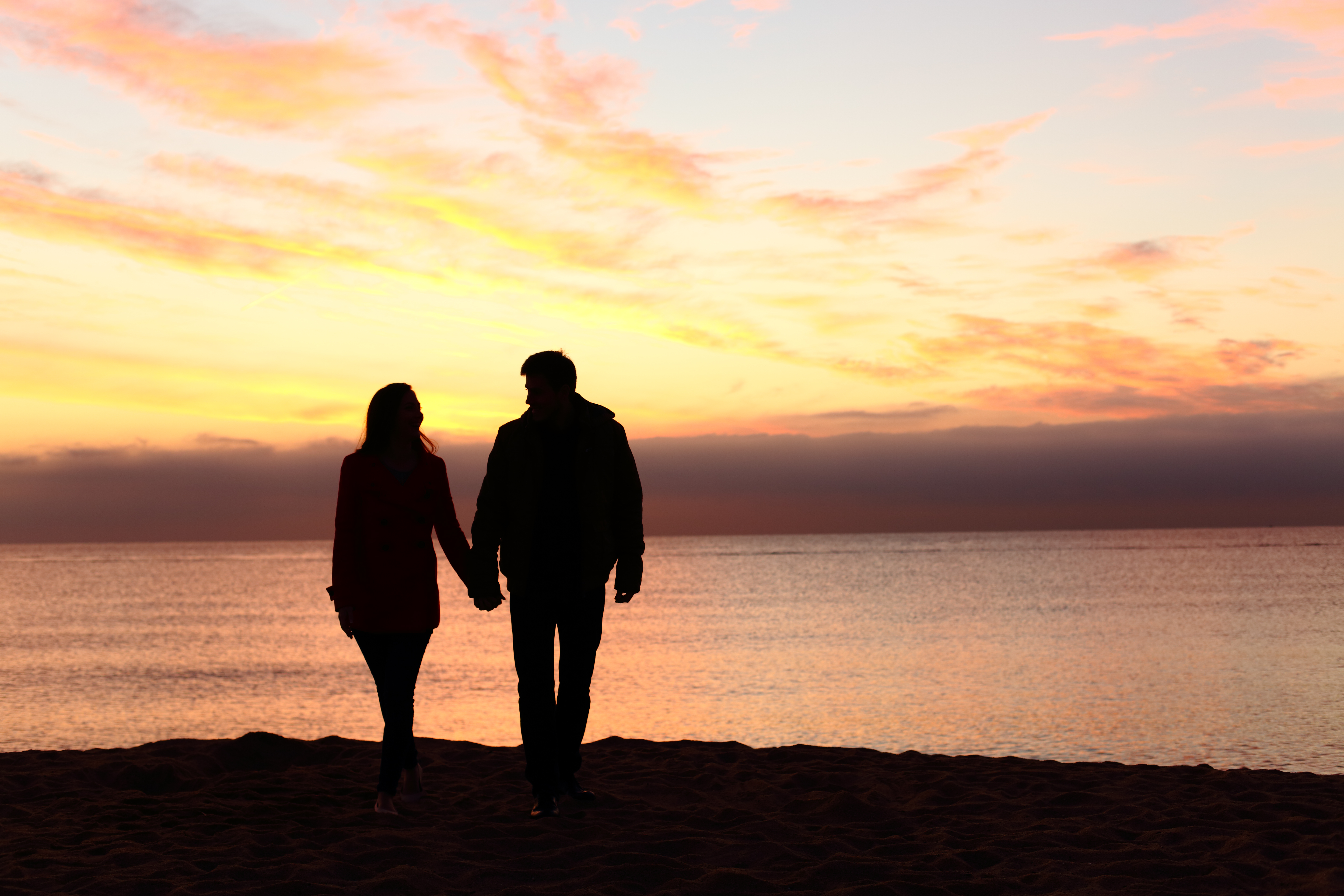 Silhouette d'un couple regardant le coucher de soleil sur une plage | Source : Shutterstock