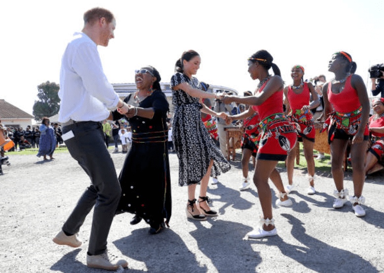 Lors de leur tournée en Afrique, Prince Harry et Meghan Markle dansent avec les habitants lors d'une visite organisée à l'initiative de la justice dans la banlieue de Nyanga, le 23 septembre 2019 à Cape Town, en Afrique du Sud. | Source: Getty Images