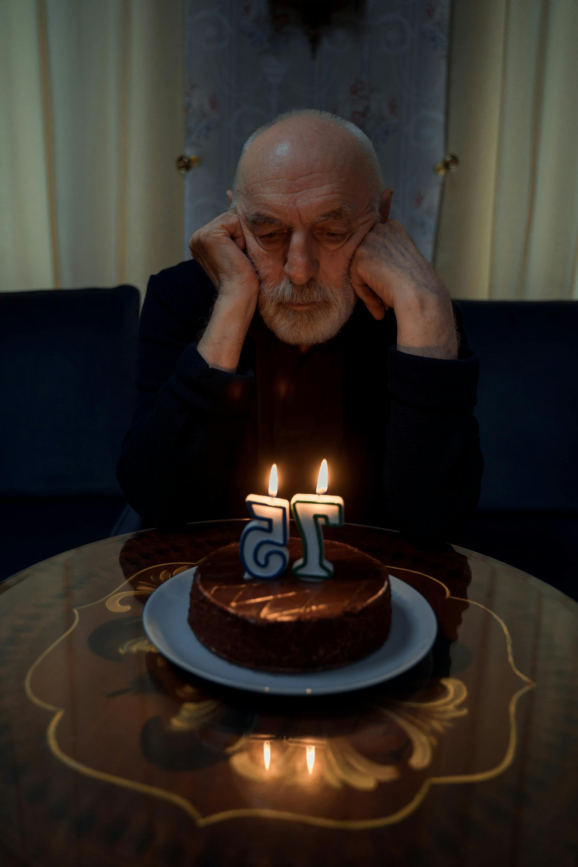 Un vieil homme triste qui regarde son gâteau d'anniversaire | Source : Pexels