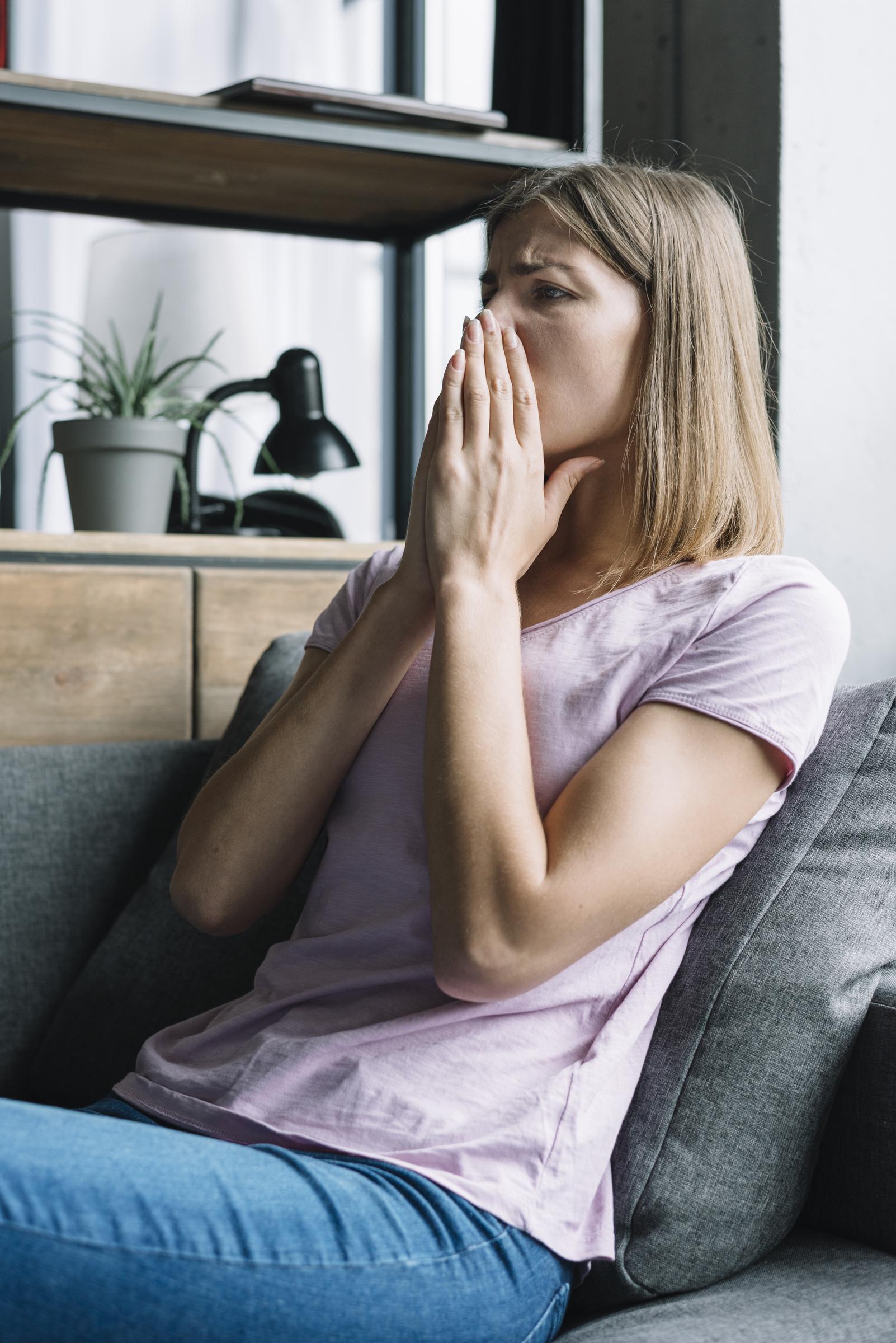 Une femme en détresse assise sur le canapé | Source : Freepik