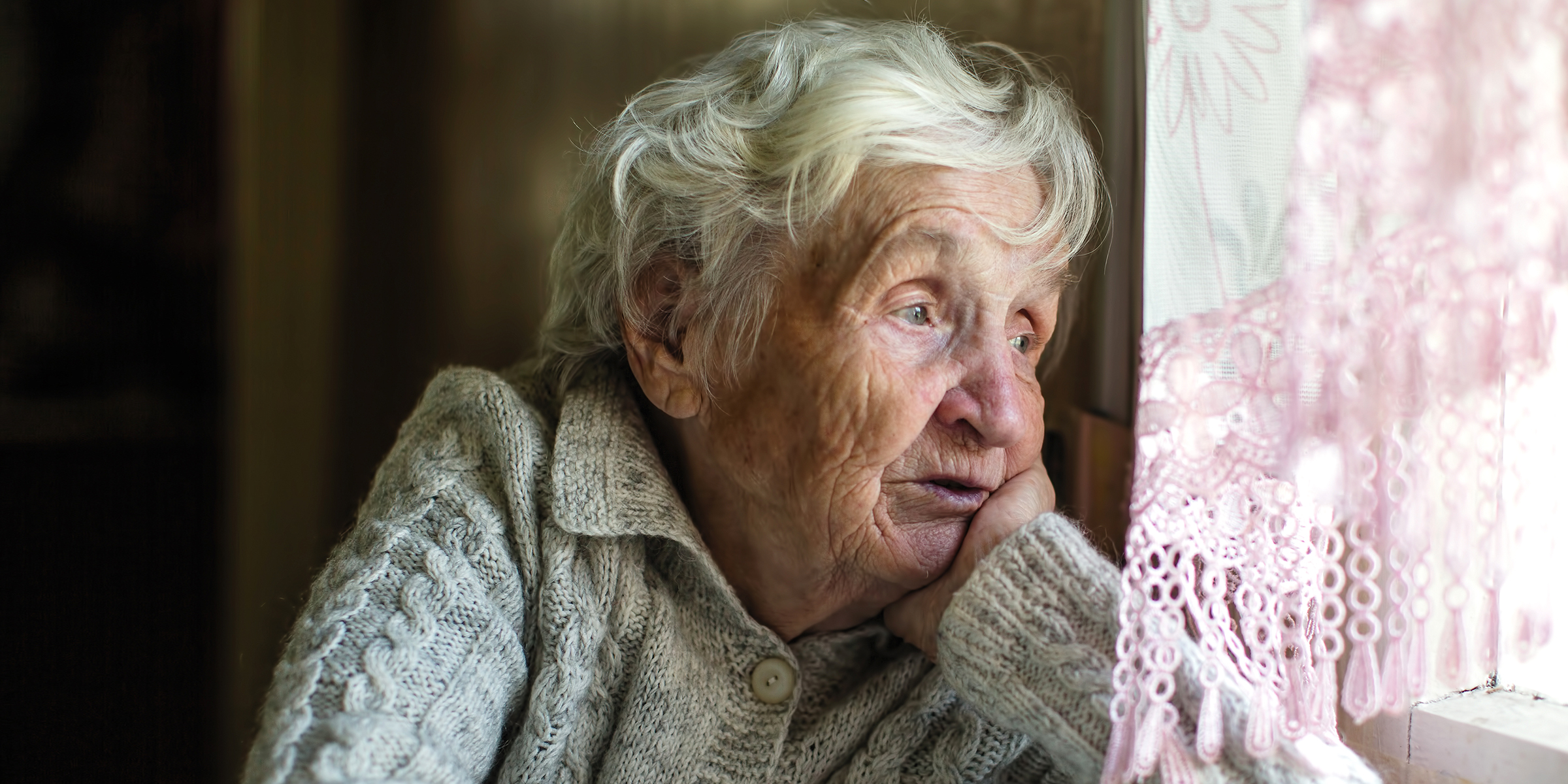 Une femme âgée triste qui regarde par la fenêtre | Source : Shutterstock