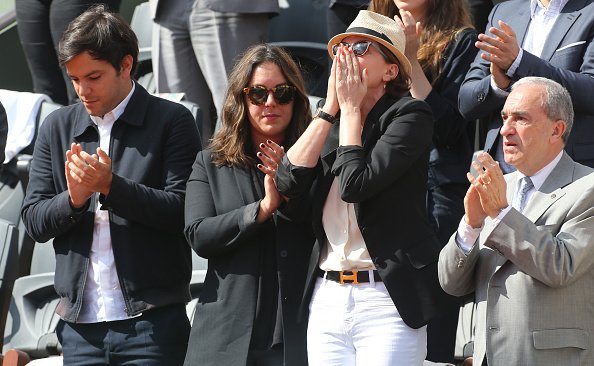 Cendrine Dominguez (C), son fils Léo Dominguez, sa fille Léa Dominguez et Jean Gachassin assistent à l'hommage rendu au champion de France de tennis Patrice Dominguez. |Photo :Getty Images.