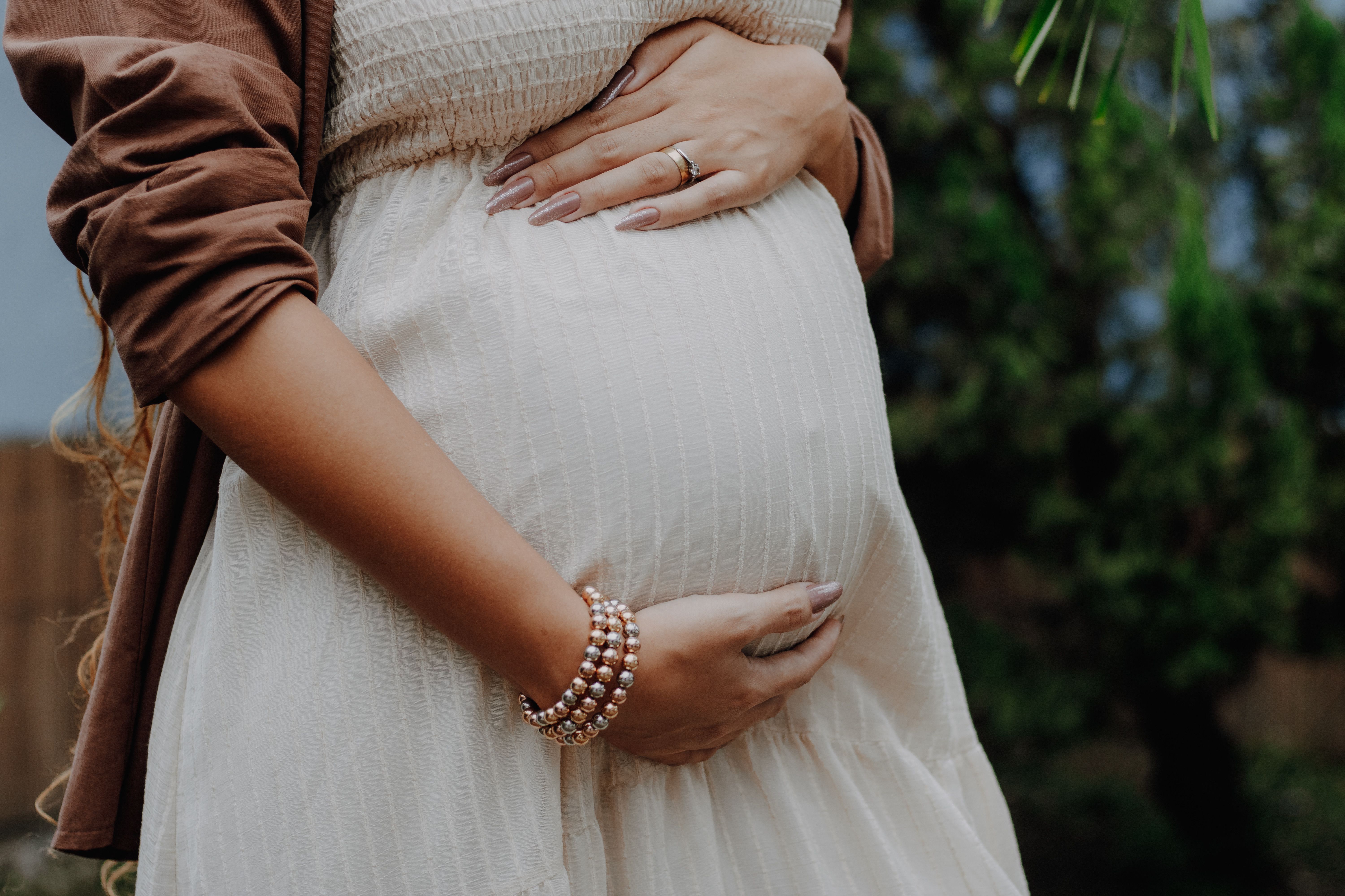 Un portrait serein en extérieur d'une femme enceinte qui caresse tendrement son ventre | Source : Pexels