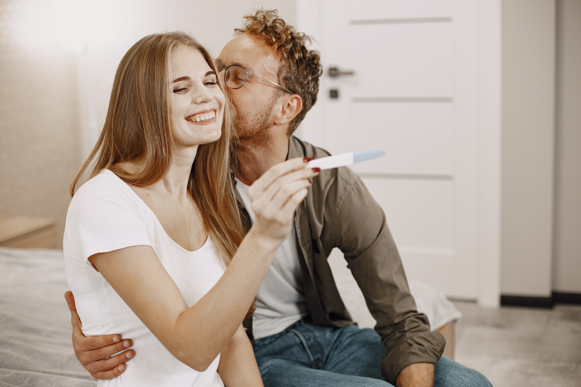 Une femme tient un kit de test de grossesse pendant qu'un homme l'embrasse | Source : Pexels