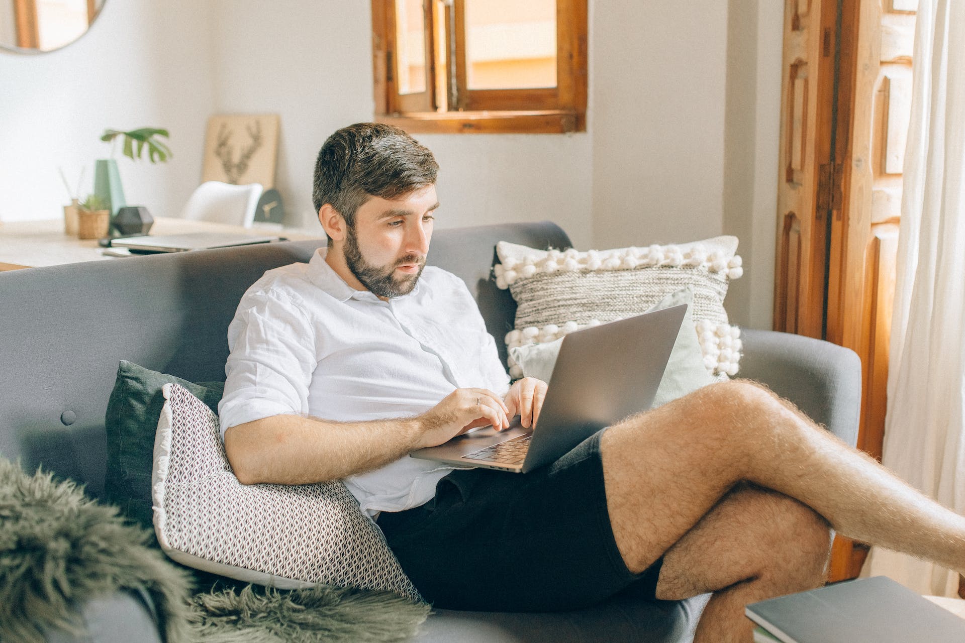 Homme utilisant un ordinateur portable sur un canapé | Source : Pexels
