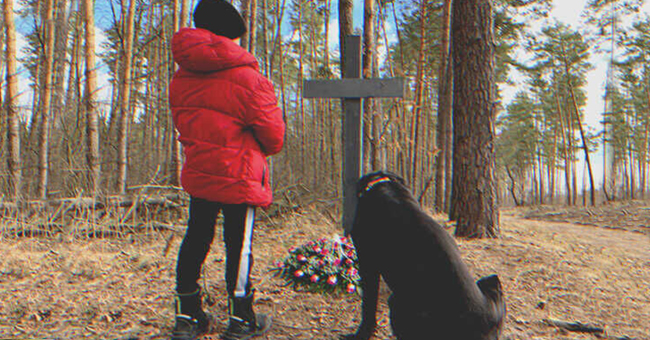 Un petit orphelin et un chien près d'une tombe | Source : Shutterstock