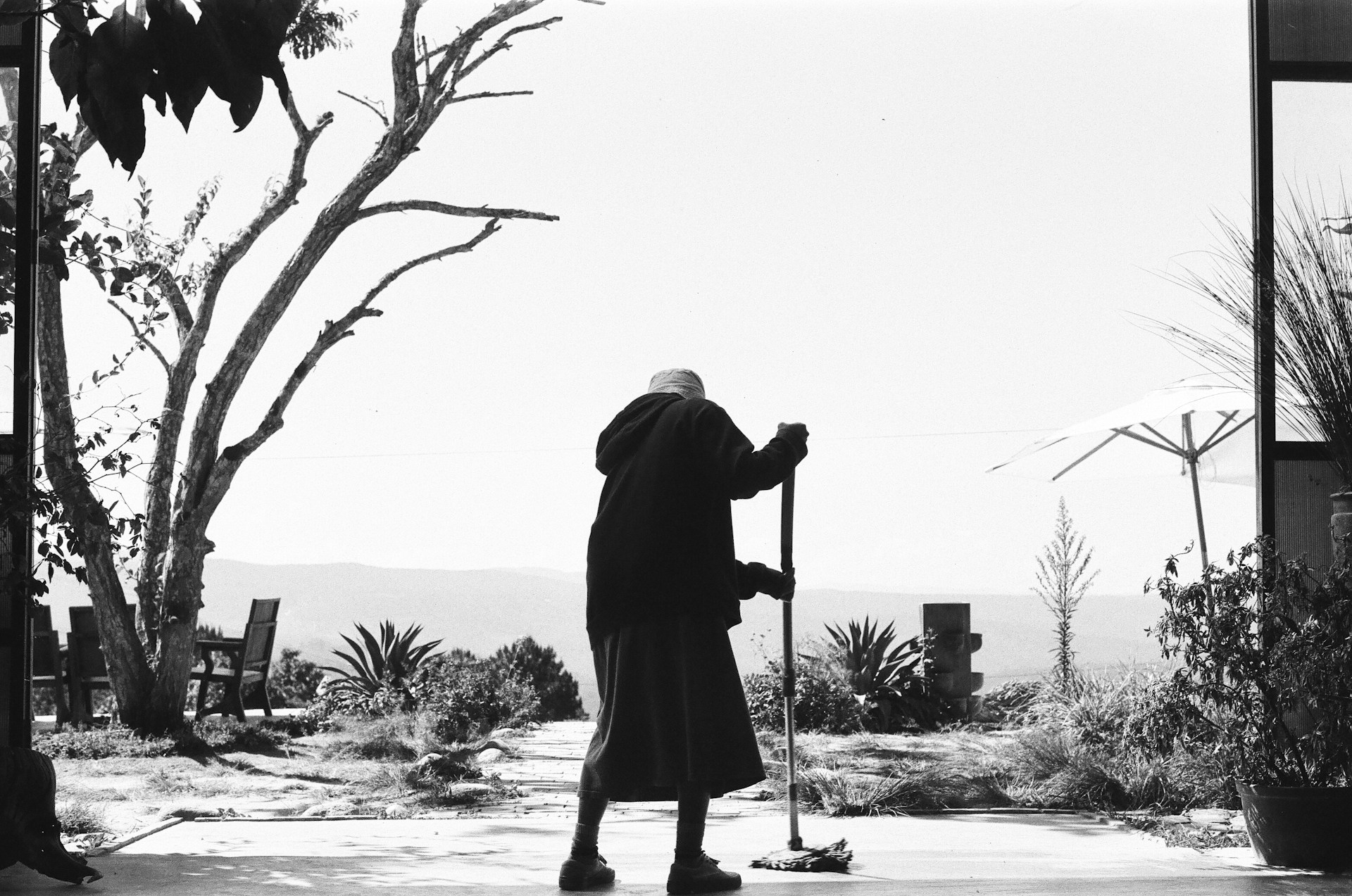 Photo en niveaux de gris d'une femme âgée qui nettoie le sol | Source : Unsplash