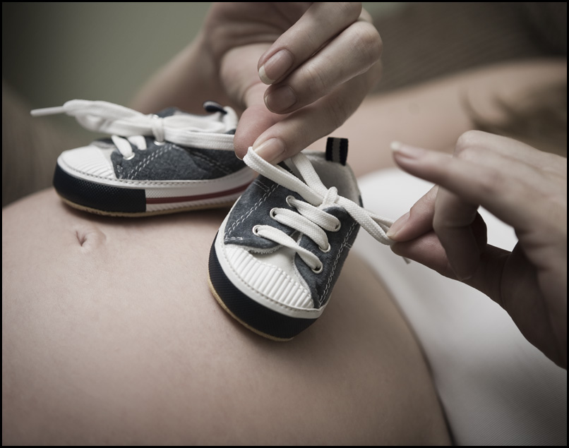 Chaussures de bébé posées sur le ventre d'une femme enceinte | Source : Flickr