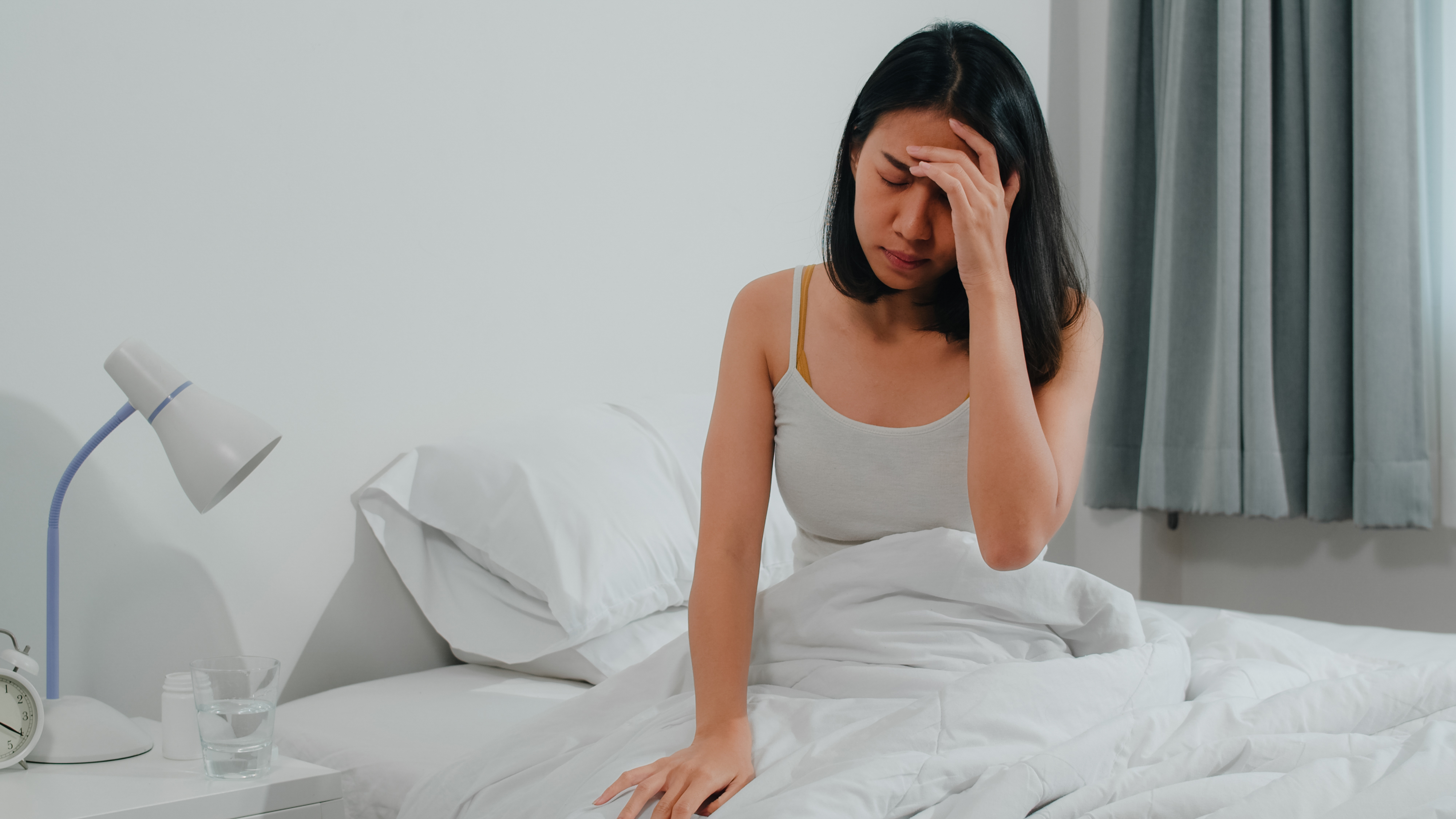 Une jeune femme stressée assise dans son lit | Source : Freepik