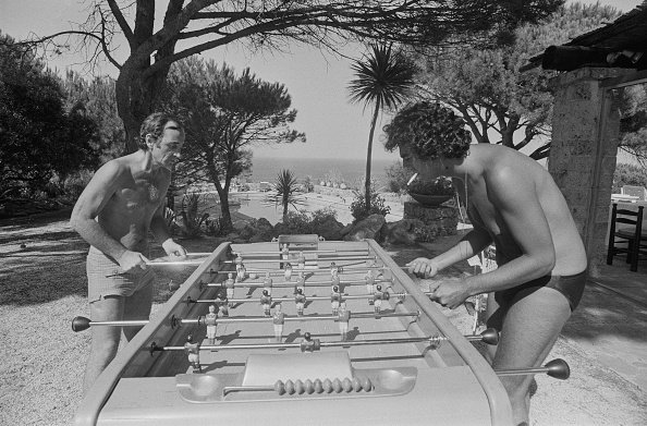 Enrico Macias, jouant au baby-foot avec Charles Aznavour pendant leurs vacances d'été à St-Tropez, 16 août 1974. | Photo : Getty Images