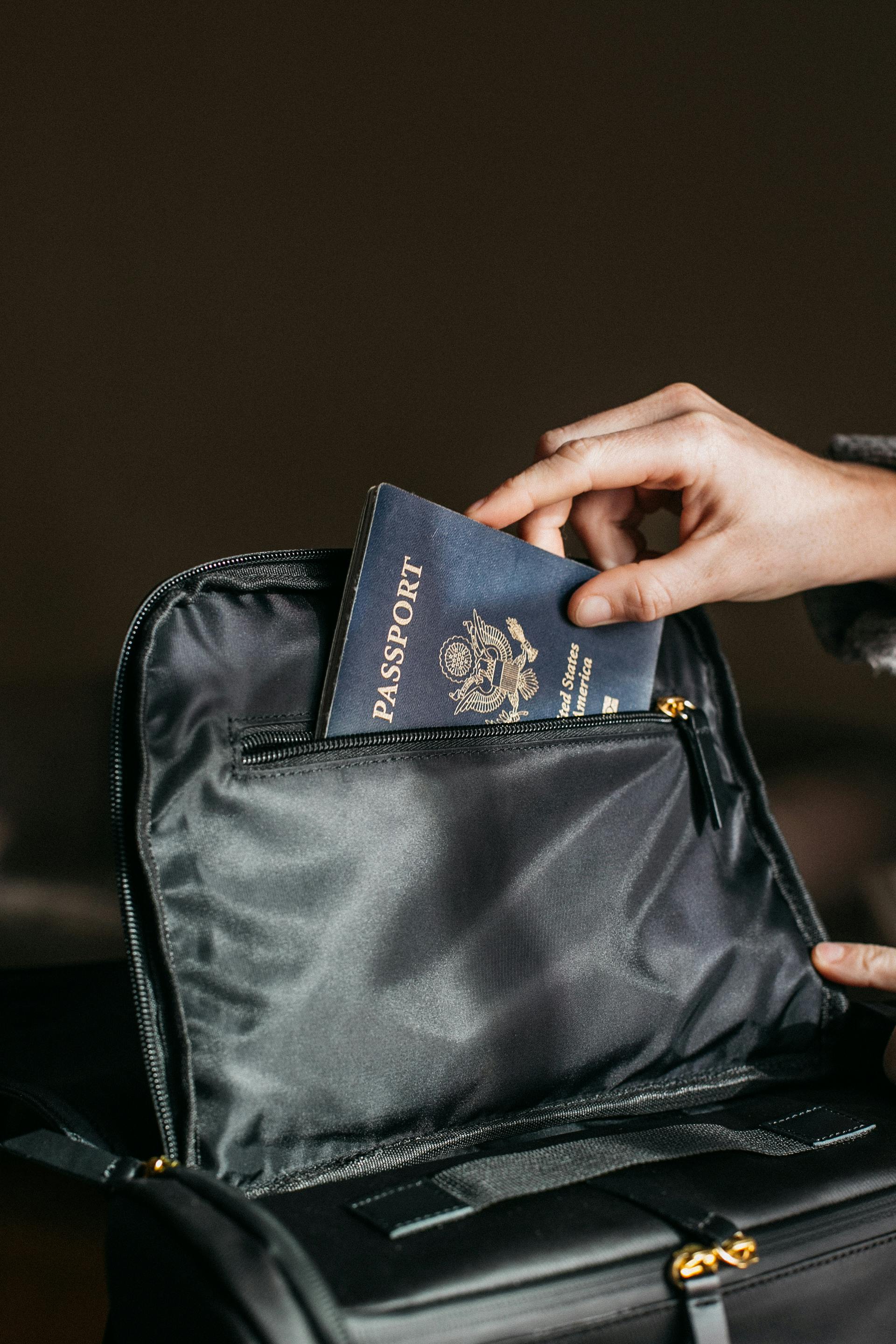 Gros plan d'une personne mettant un passeport dans un sac noir | Source : Pexels