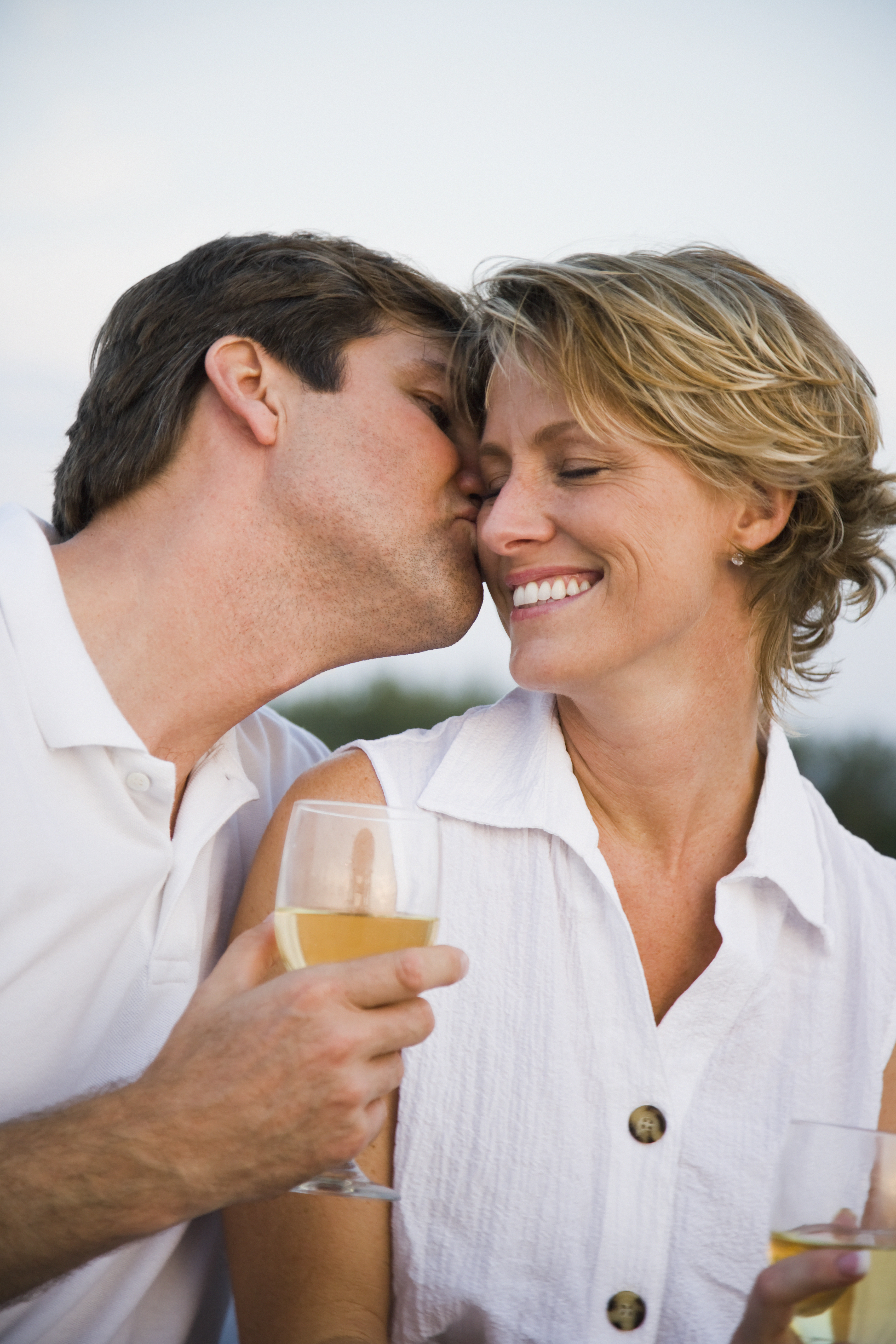 Un homme donnant à sa femme un baiser sur la joue lors d'un dîner | Source : Getty Images
