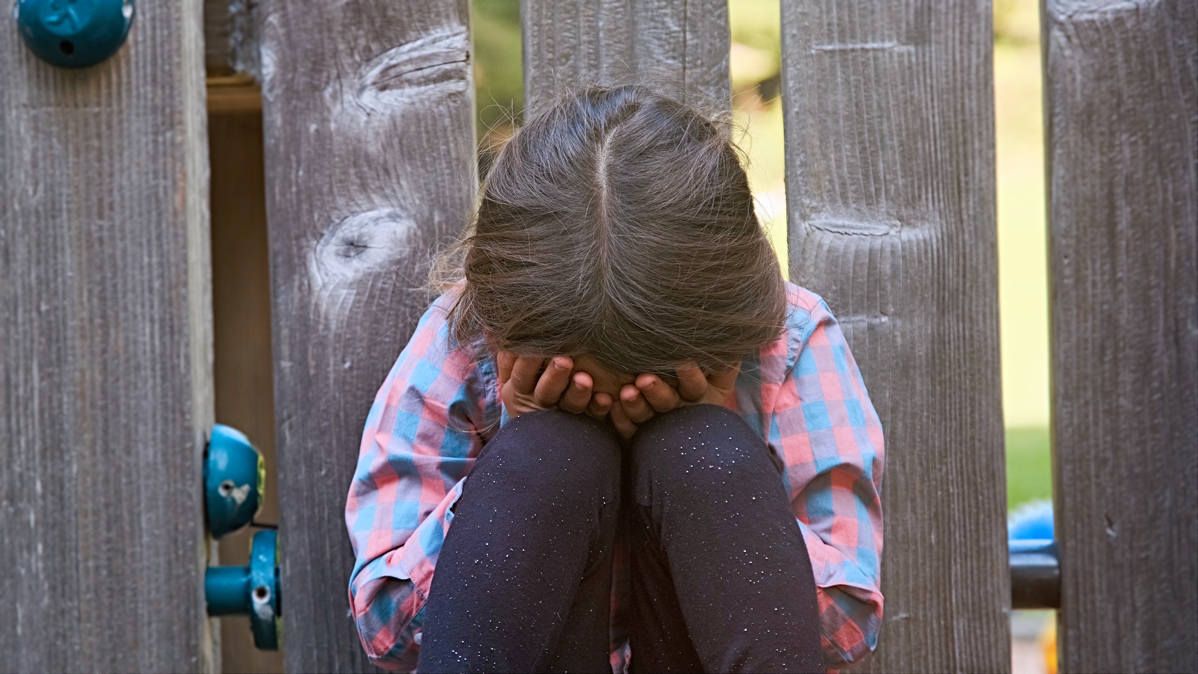 Une petite fille en pleurs, assise par terre, se couvrant le visage I Photo d'illustration I Source : Getty Images
