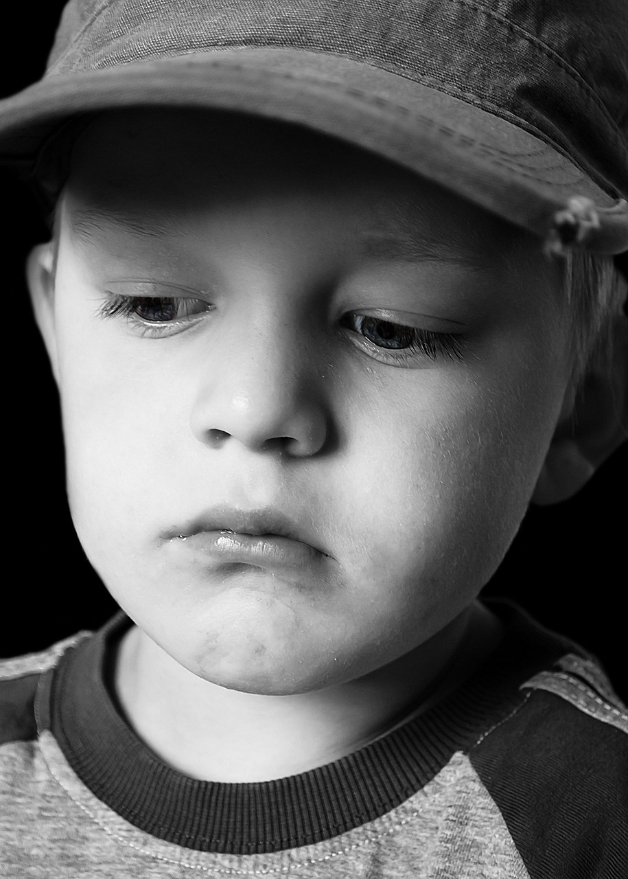 Portrait en niveaux de gris d'un petit garçon triste aux yeux baissés | Source : Pixabay